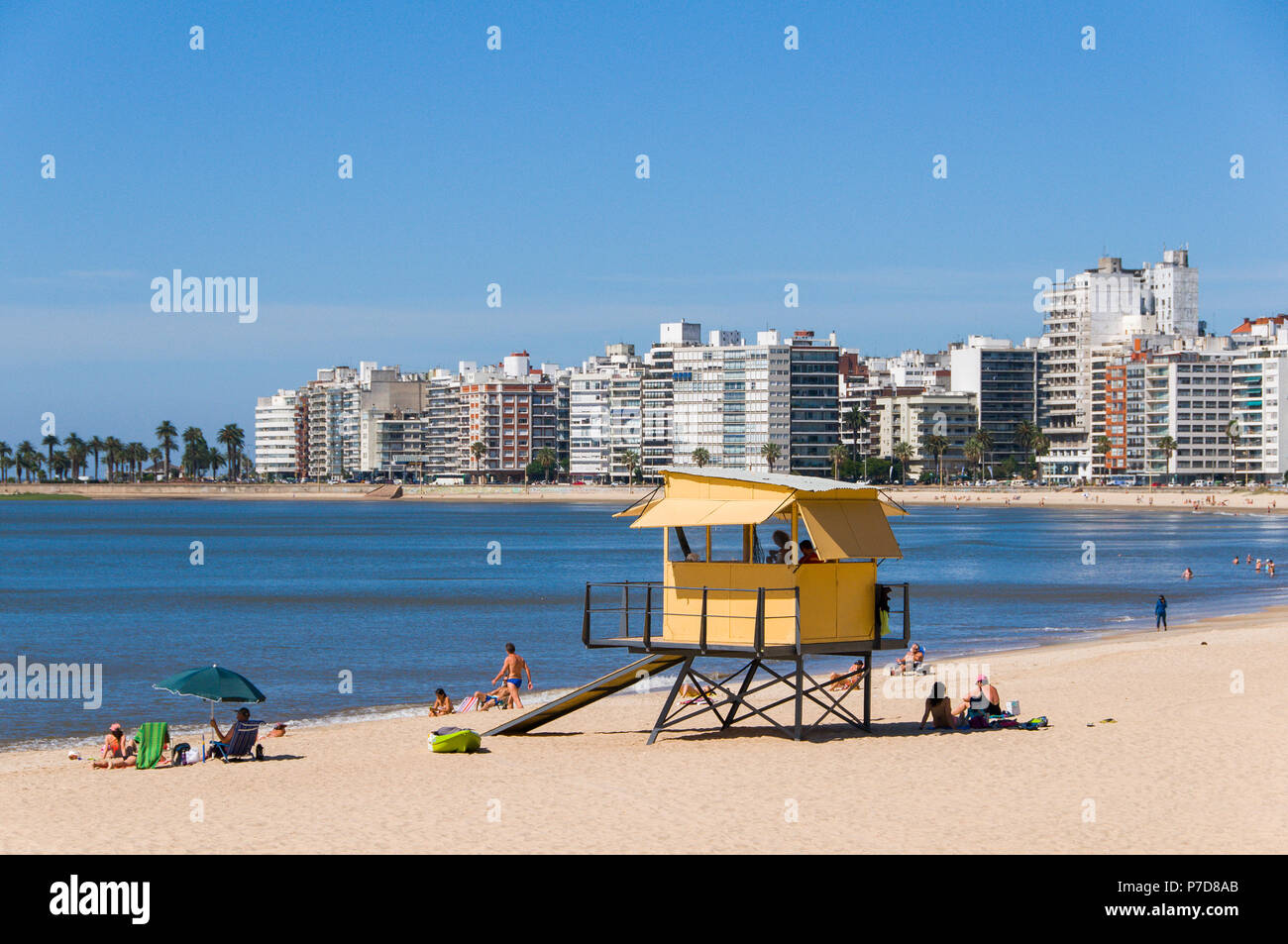 Swimmers at the city beach, lifeguard tower and skyscrapers in Montevideo, Uruguay Stock Photo