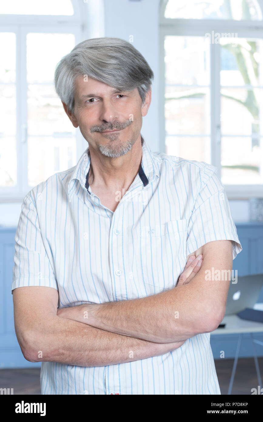 Man standing in his office with his arms crossed Stock Photo