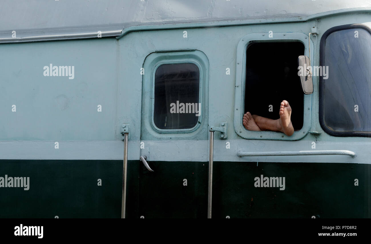 North Korean train driver resting with bare feet hanging out of the ...