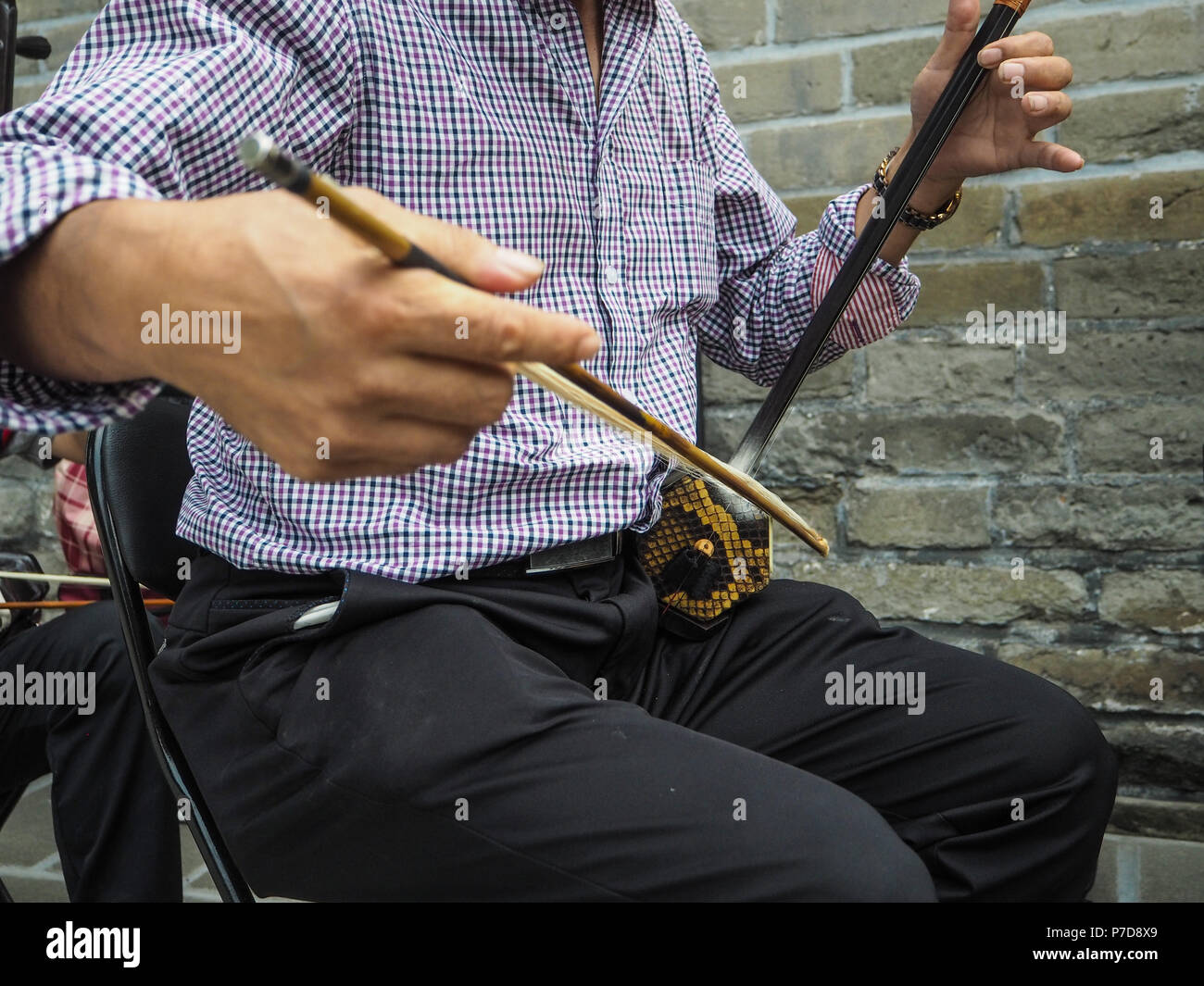 Chinese man playing the Chinese violin called erhu in a small ensemble outdoor at the temple of Heaven Stock Photo
