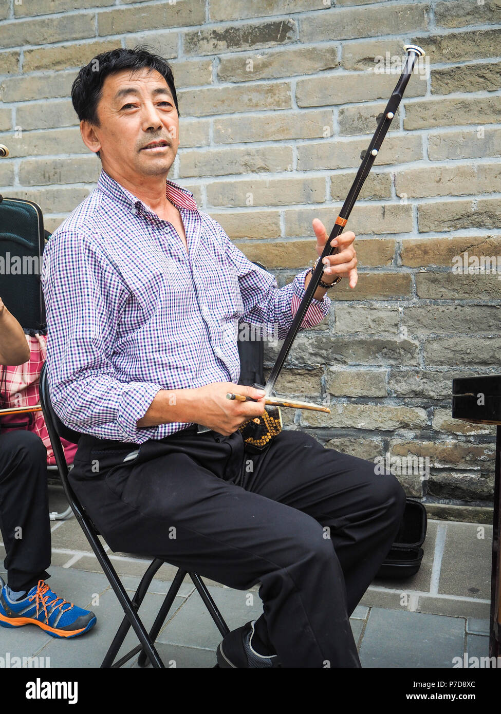 Beijing, China - September 2017: Chinese man playing the Chinese violin called erhu in a small ensemble outdoor at the temple of Heaven Stock Photo