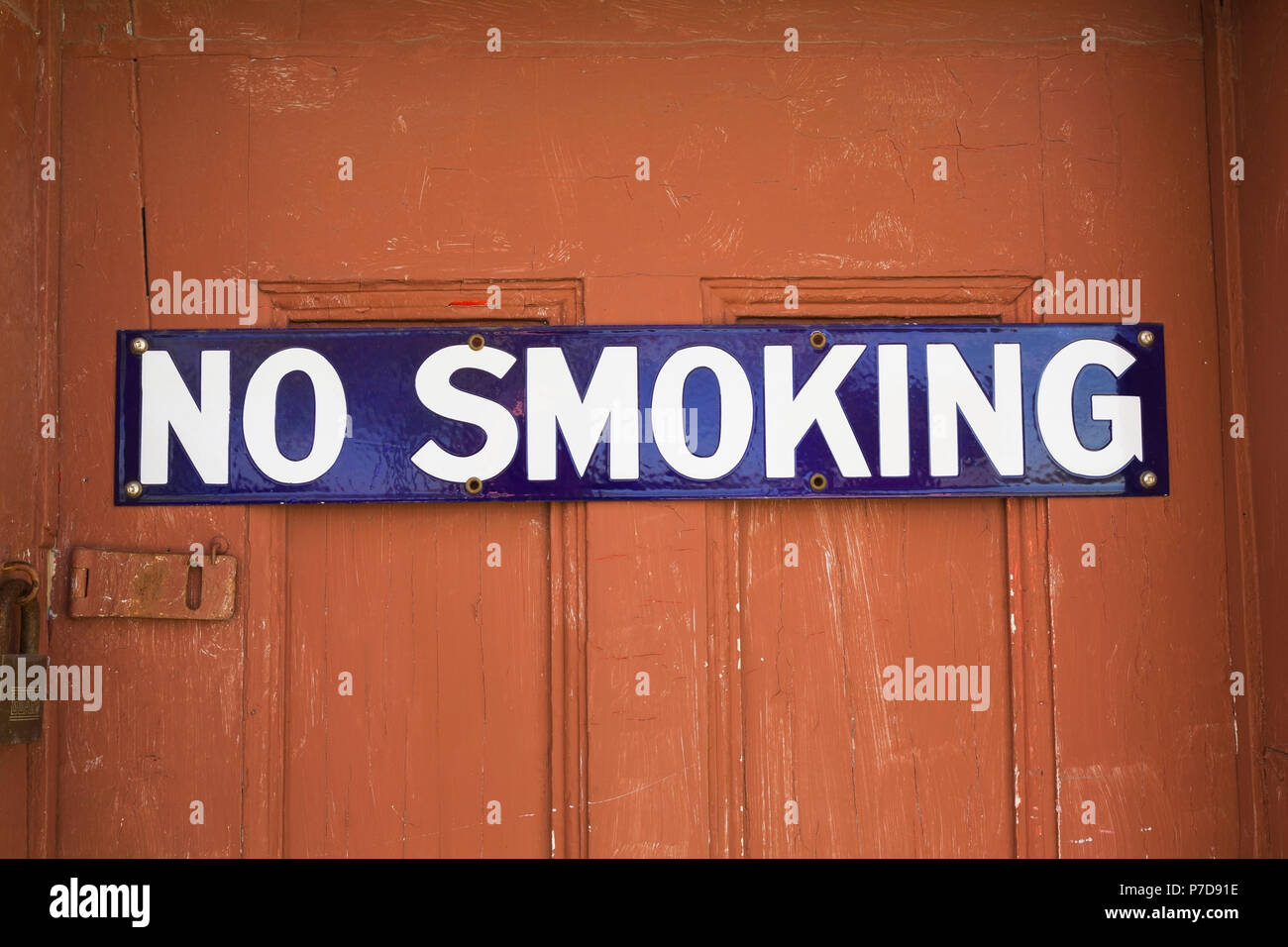 White and blue No Smoking sign on reddish brown wooden entrance door, Quebec, Canada Stock Photo