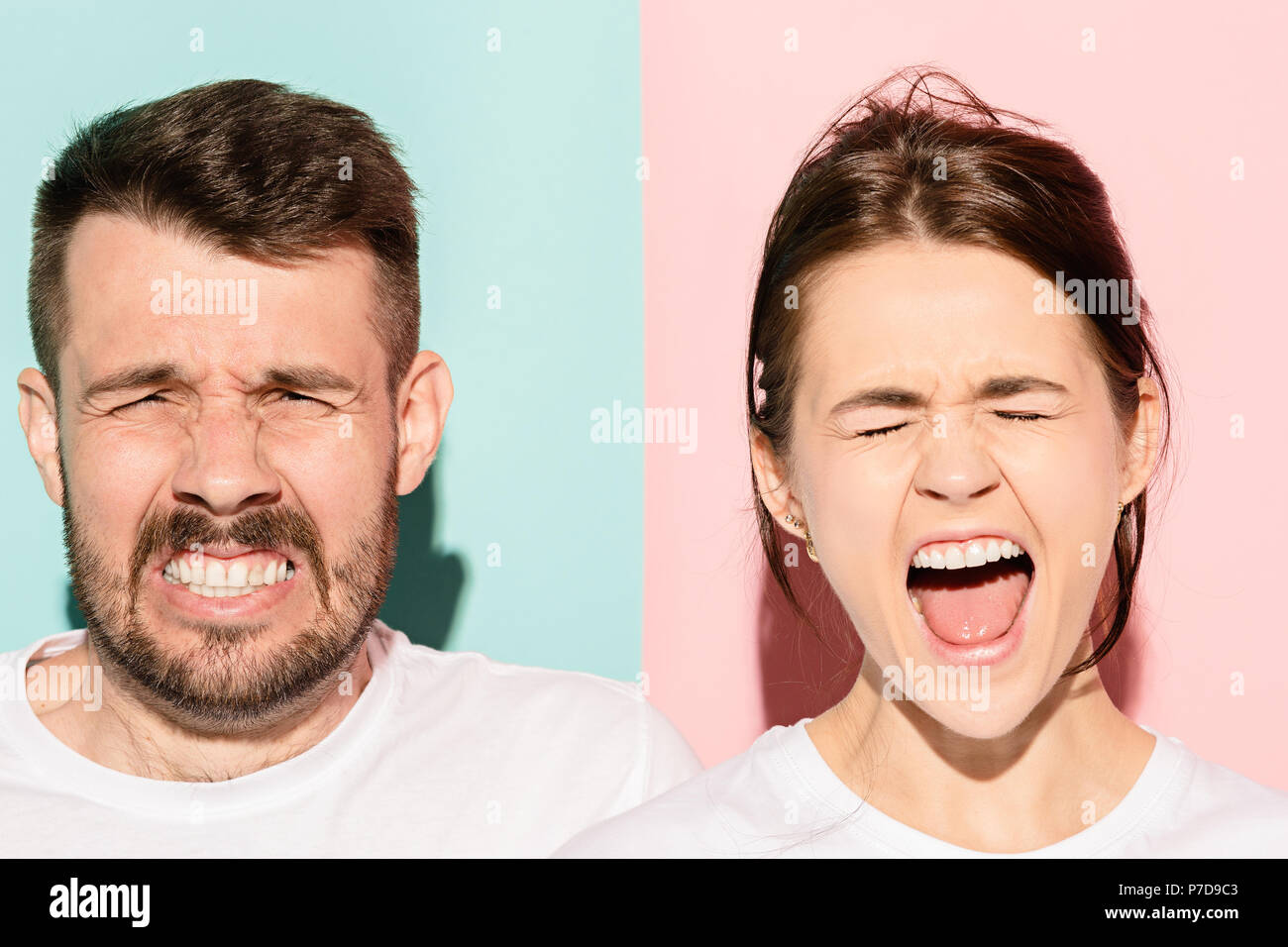 Closeup portrait of young couple, man, woman. One being excited happy smiling, other serious, concerned, unhappy on pink and blue background. Emotion contrasts Stock Photo