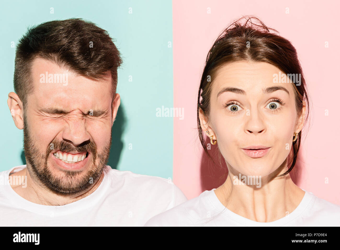 Closeup portrait of young couple, man, woman. One being excited happy smiling, other serious, concerned, unhappy on pink and blue background. Emotion contrasts Stock Photo