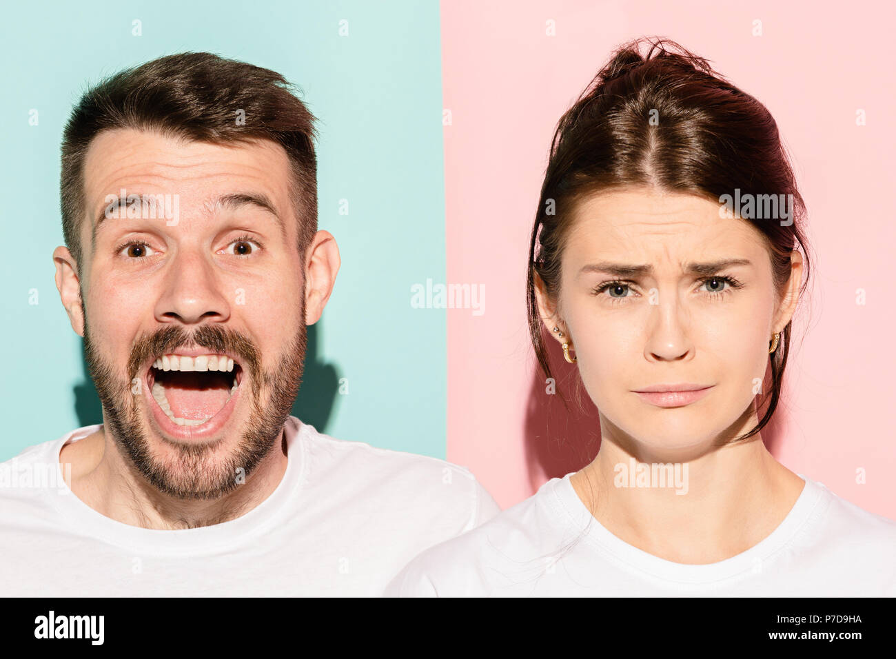 Closeup portrait of young couple, man, woman. One being excited happy smiling, other serious, concerned, unhappy on pink and blue background. Emotion contrasts Stock Photo