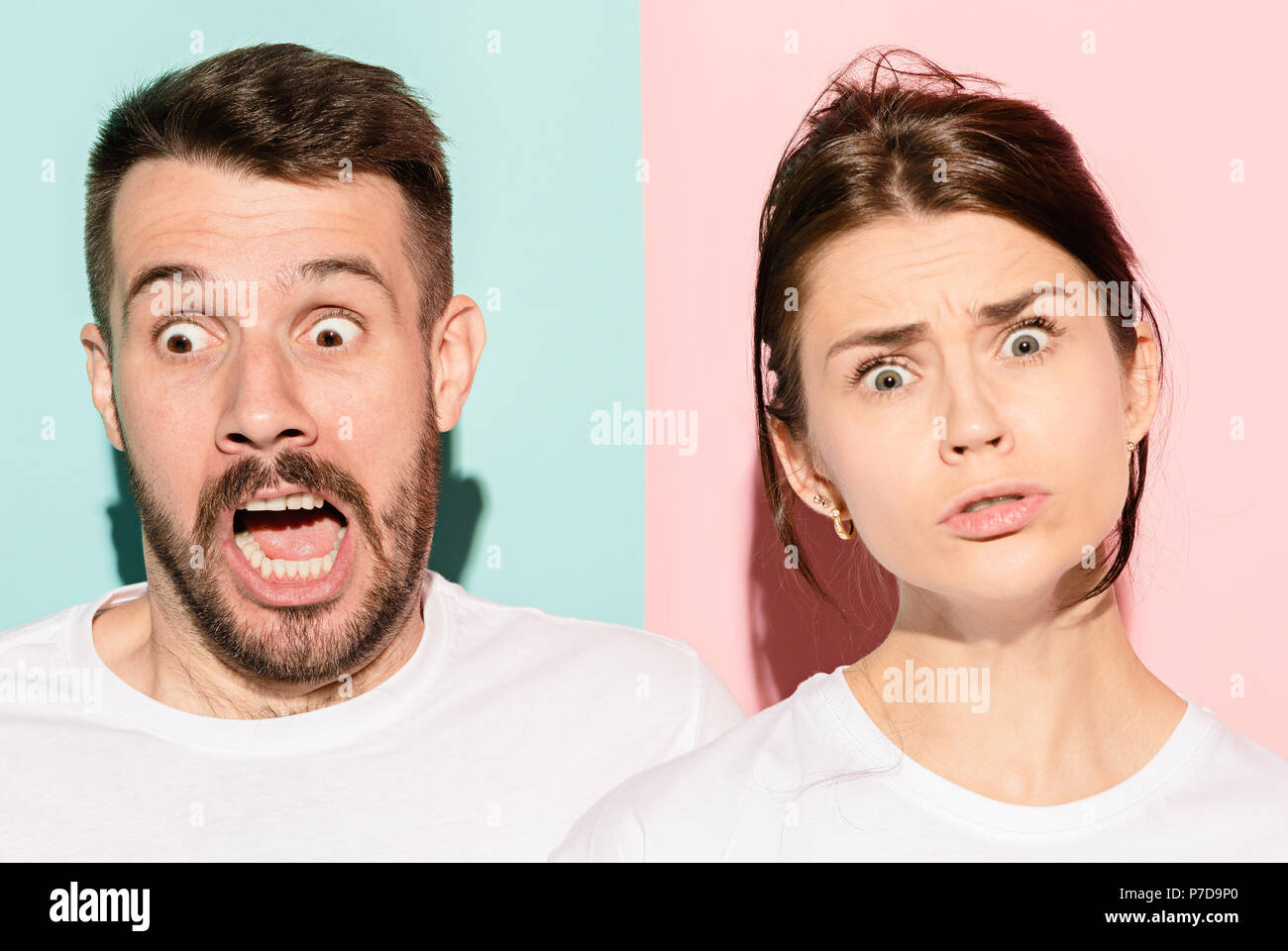 Closeup portrait of young couple, man, woman. One being excited happy smiling, other serious, concerned, unhappy on pink and blue background. Emotion contrasts Stock Photo