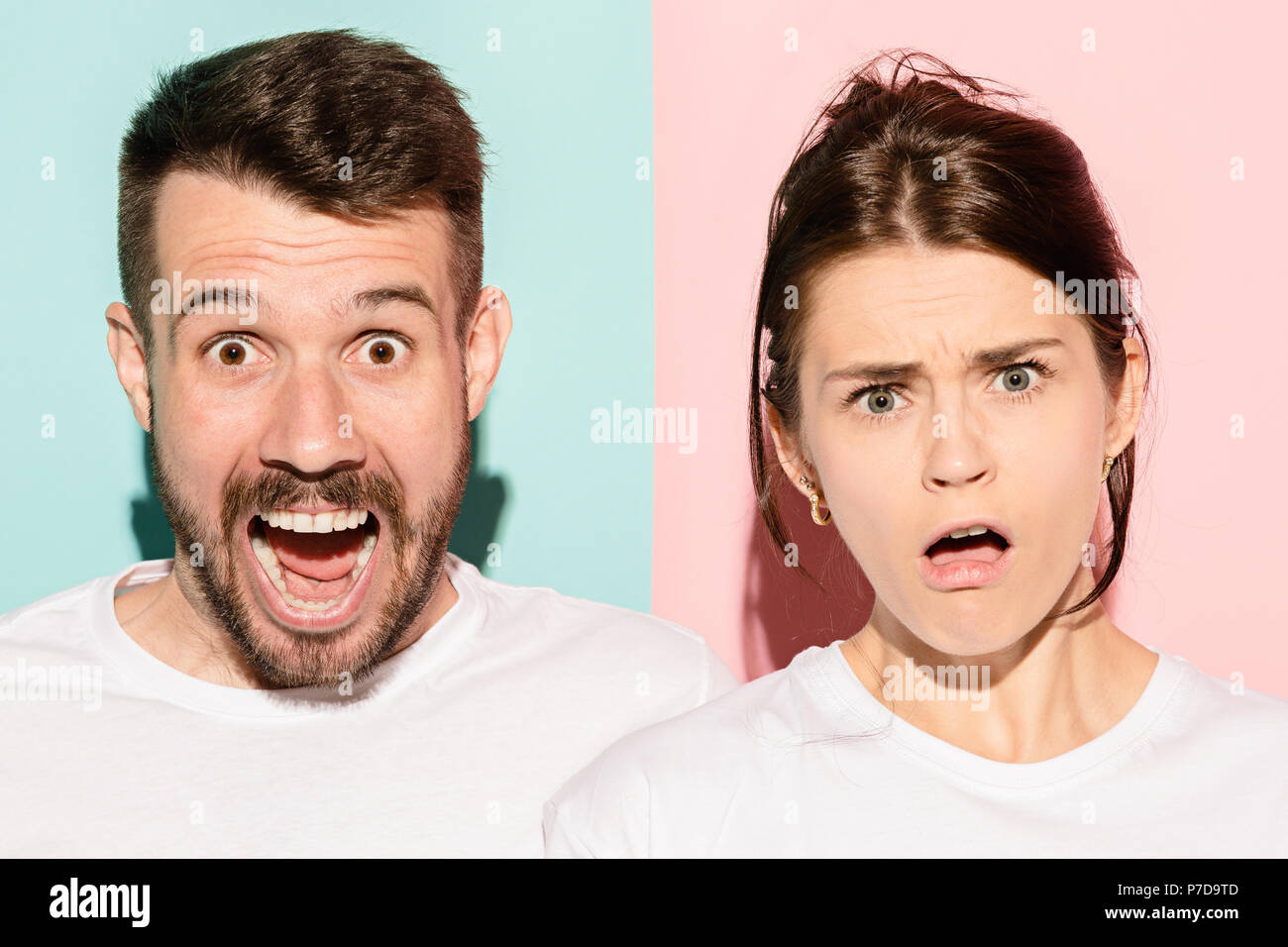 Closeup portrait of young couple, man, woman. One being excited happy smiling, other serious, concerned, unhappy on pink and blue background. Emotion contrasts Stock Photo