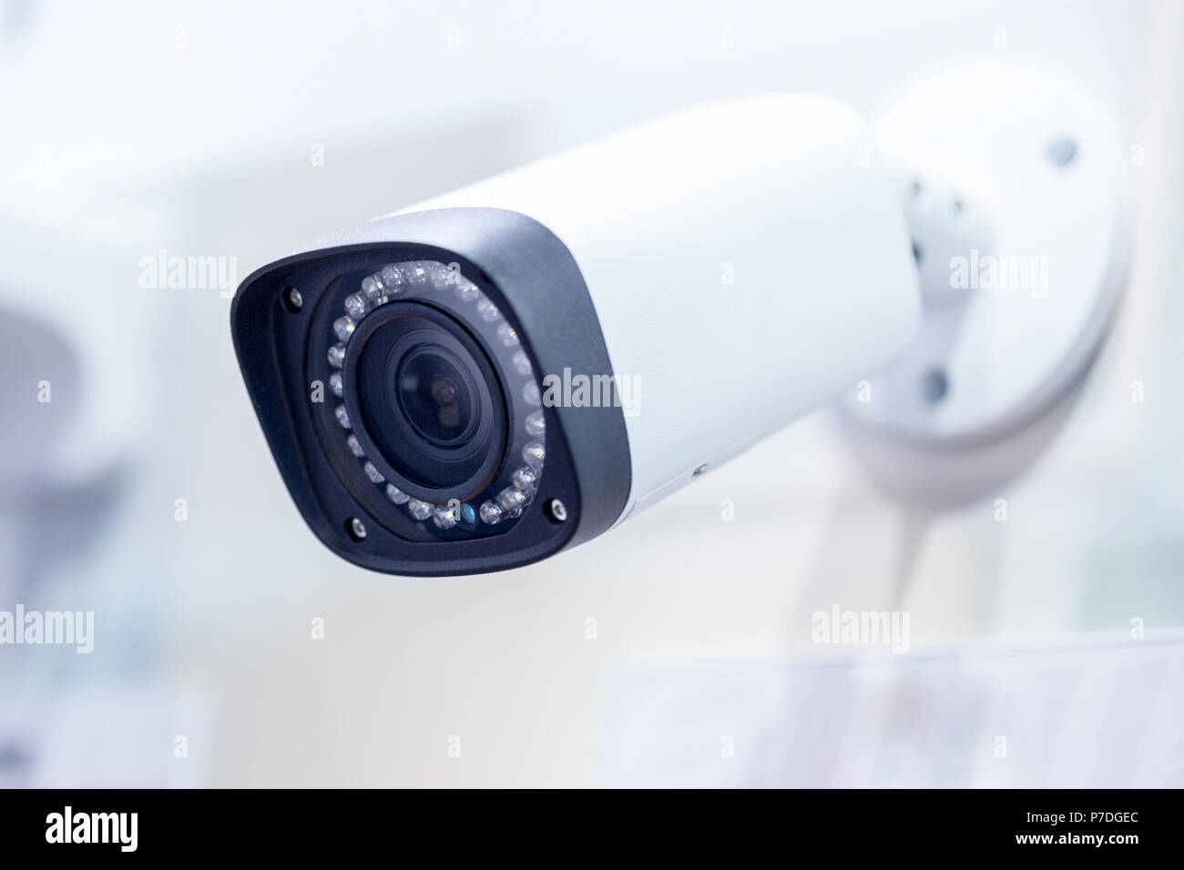 Big white professional surveillance camera. CCTV mounted on ceiling. LED IR lights around lens. Security system concept. Copyspace, neutral light blue Stock Photo