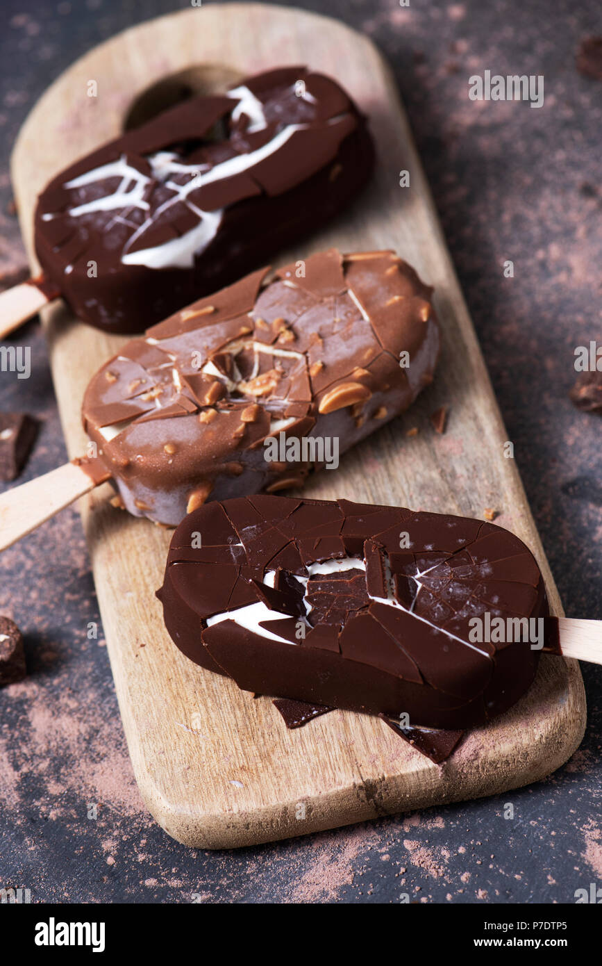 high angle view of some chocolate ice cream bars on a chopping board, placed on a dark rustic wooden table Stock Photo