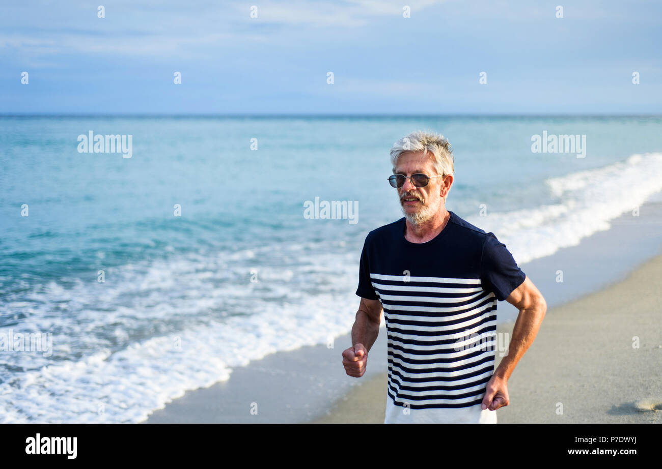 Senior man running on the beach, active vacation lifestyle Stock Photo