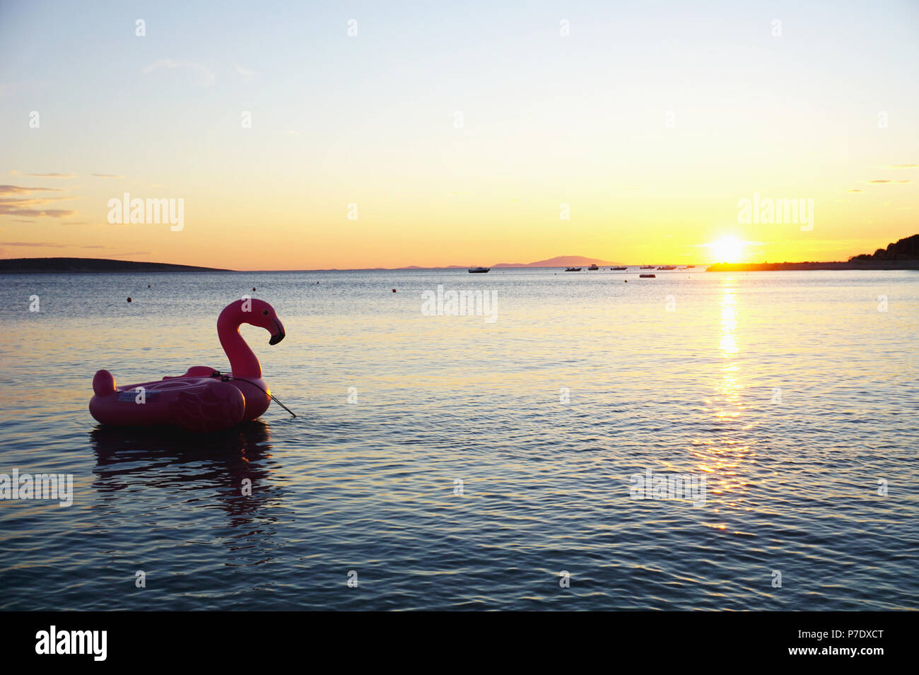 Inflatable flamingo silhouette on sea surface at beautiful sunset in Adriatic sea in Croatia Stock Photo