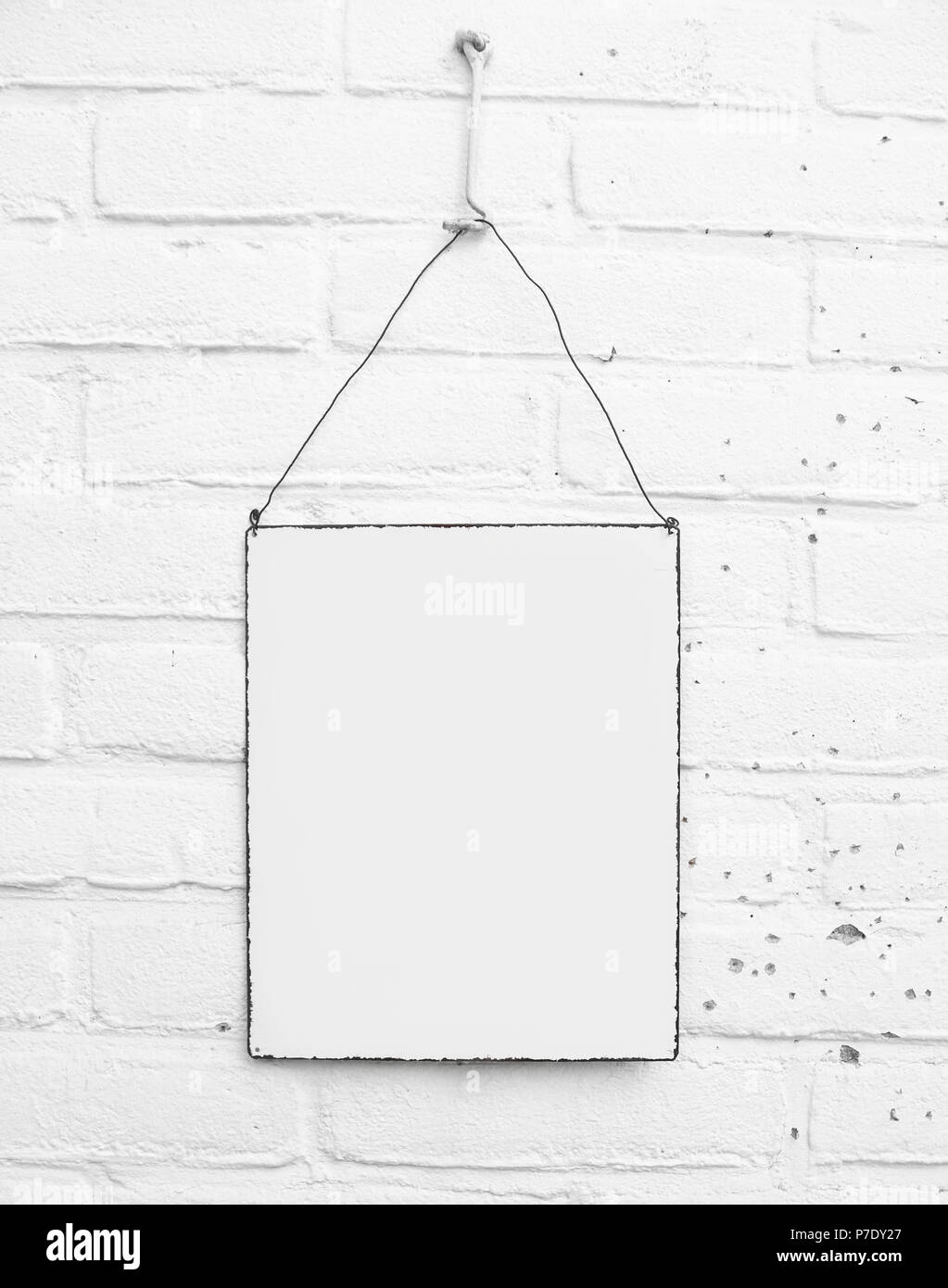 White square metal banner paper on white brick wall background - mock up - template with space for own text Stock Photo