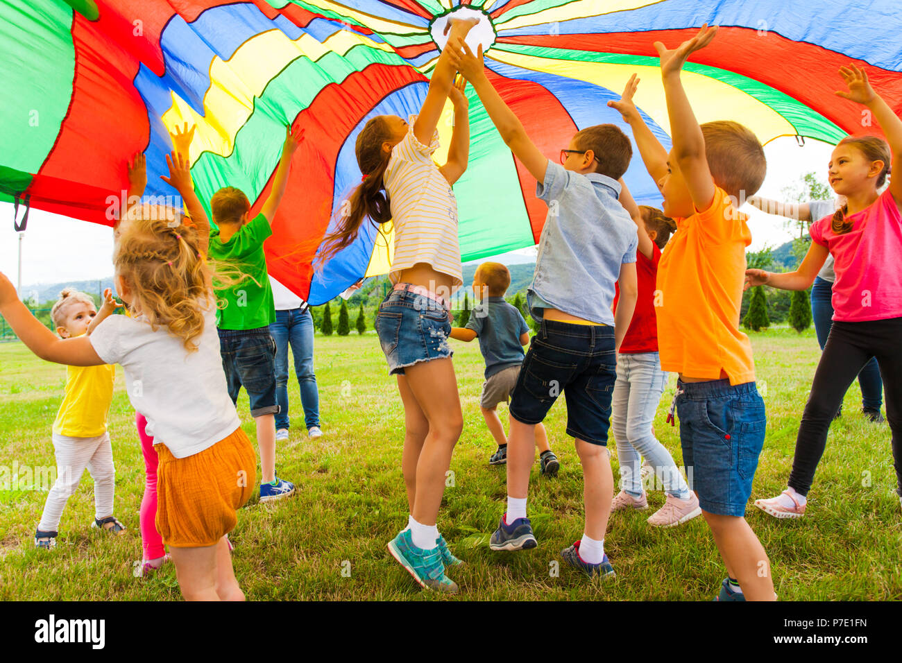 Joyful friends trying to catch flying parachute Stock Photo - Alamy