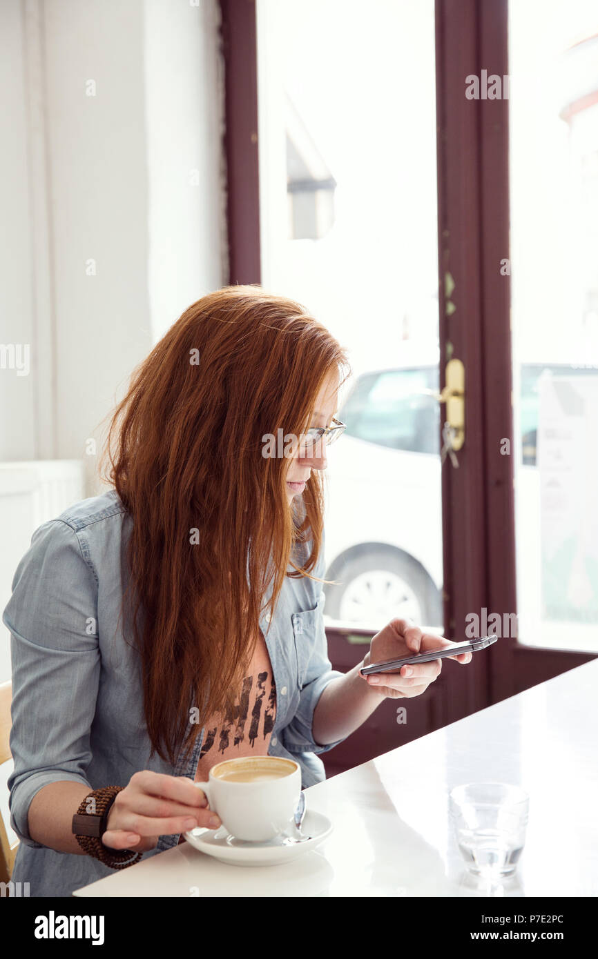 Young woman using mobile phone in cafe Stock Photo