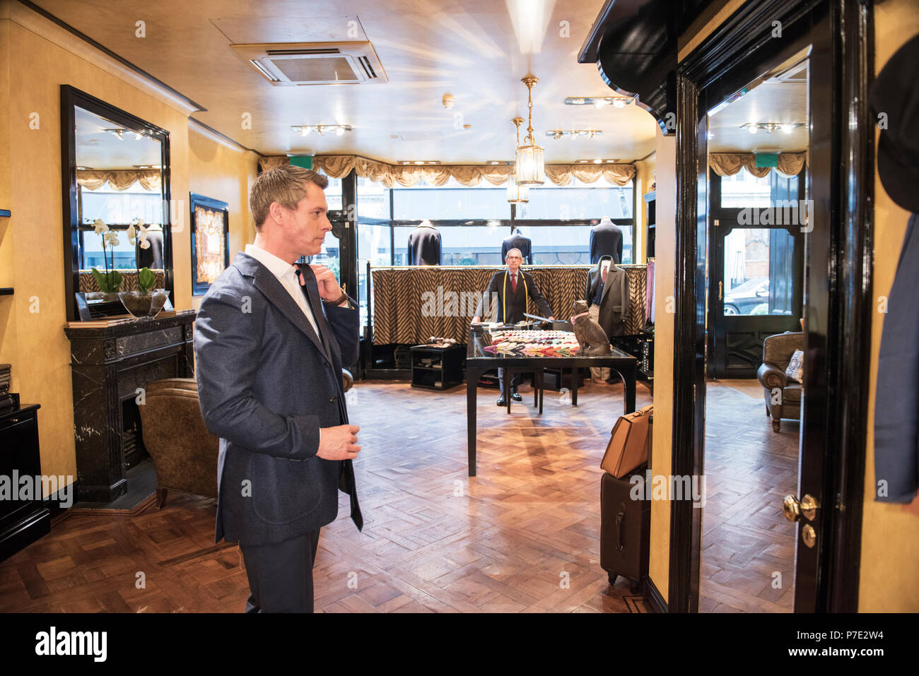 Male customer in full suit looking at mirror in tailors shop Stock Photo