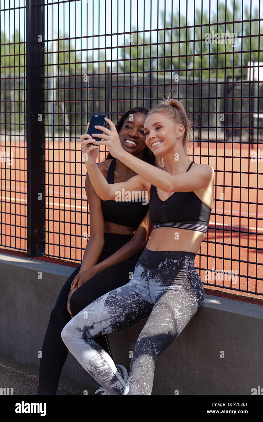 Young women smiling, reading text on mobile phone Stock Photo