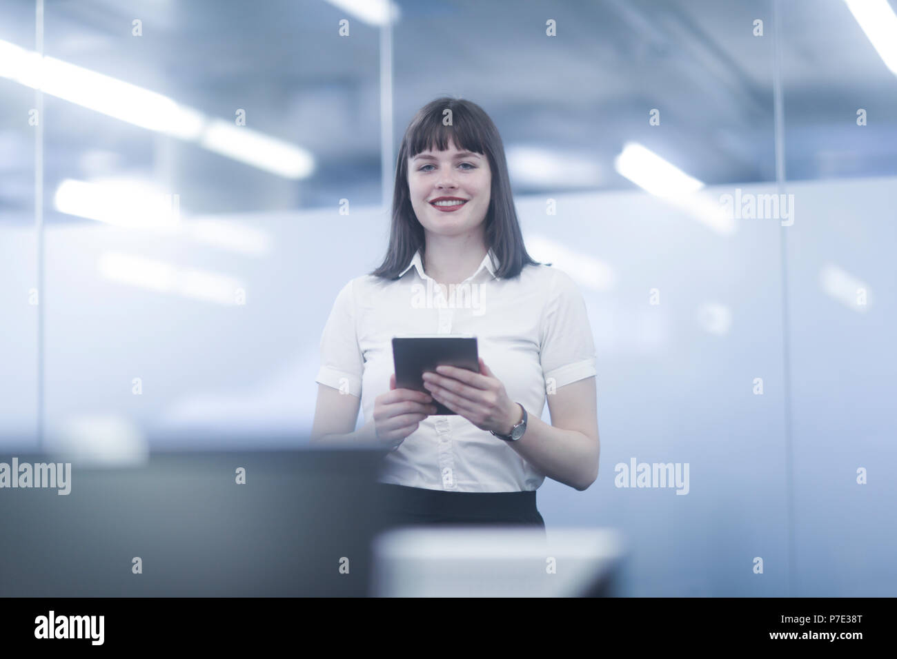 Businesswoman using digital tablet, looking at camera smiling Stock Photo