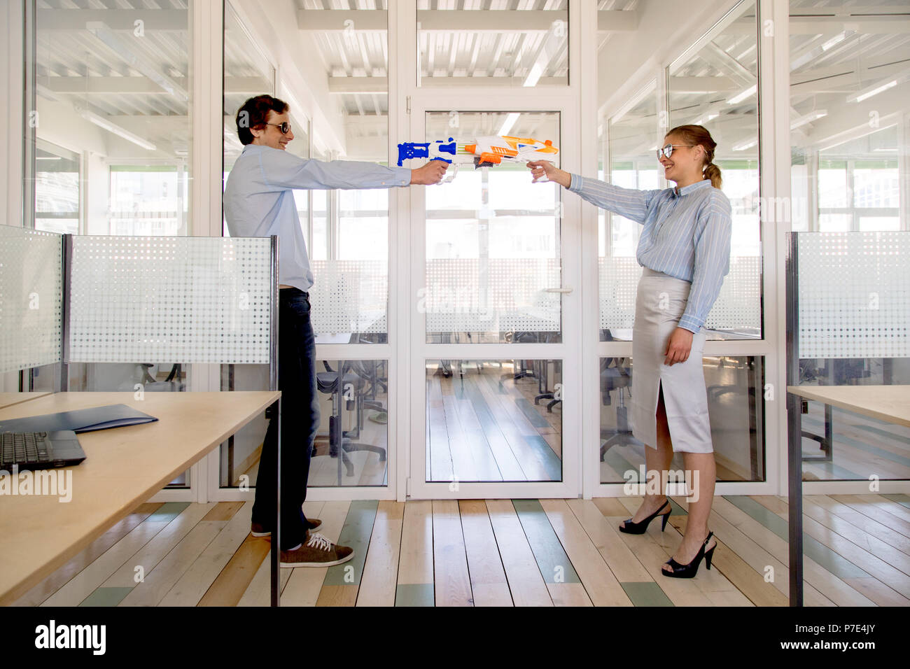 Colleagues aiming toy pistols at each other Stock Photo