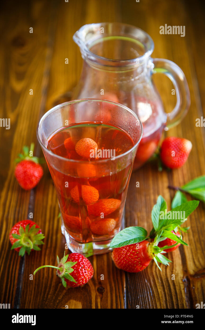 Sweet compote of ripe red strawberries in a glass decanter on a table Stock Photo