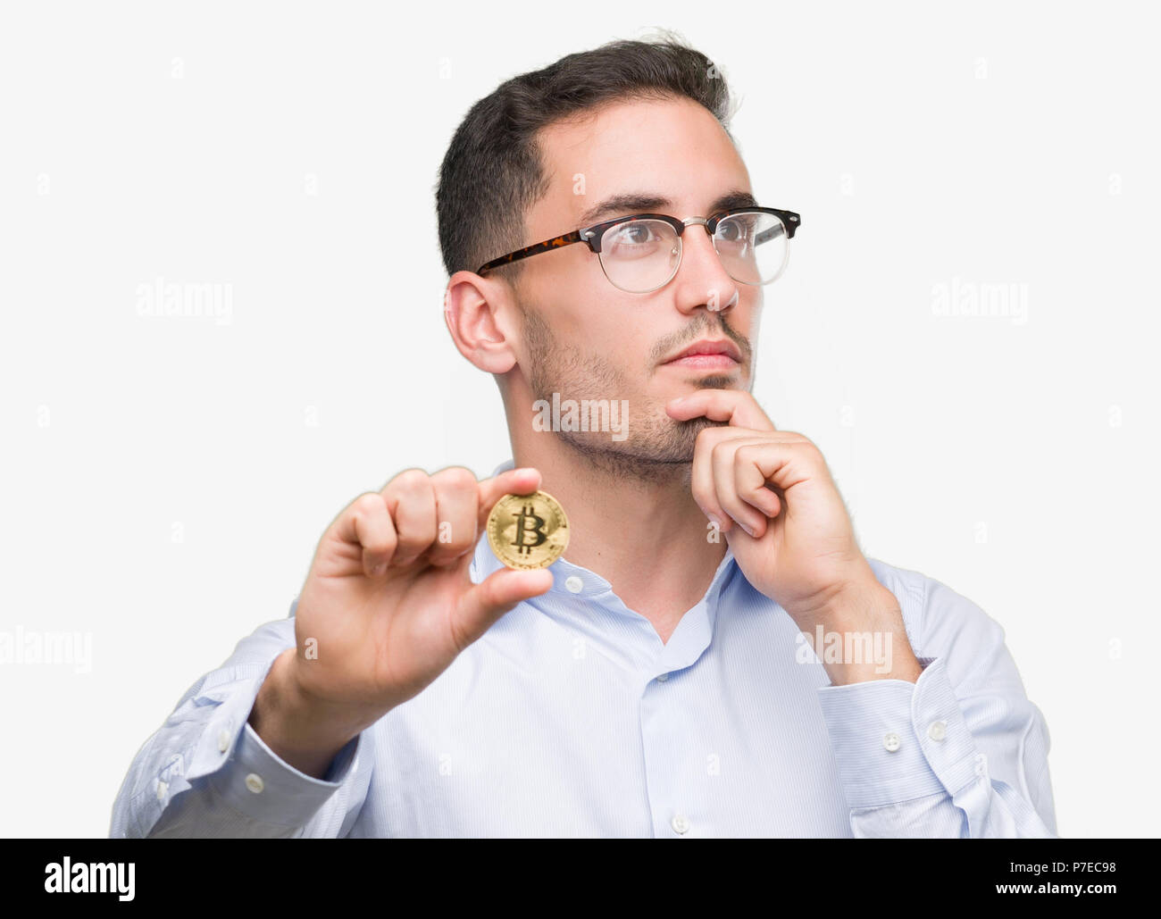 Handsome young man holding bitcoin serious face thinking about question,  very confused idea Stock Photo - Alamy