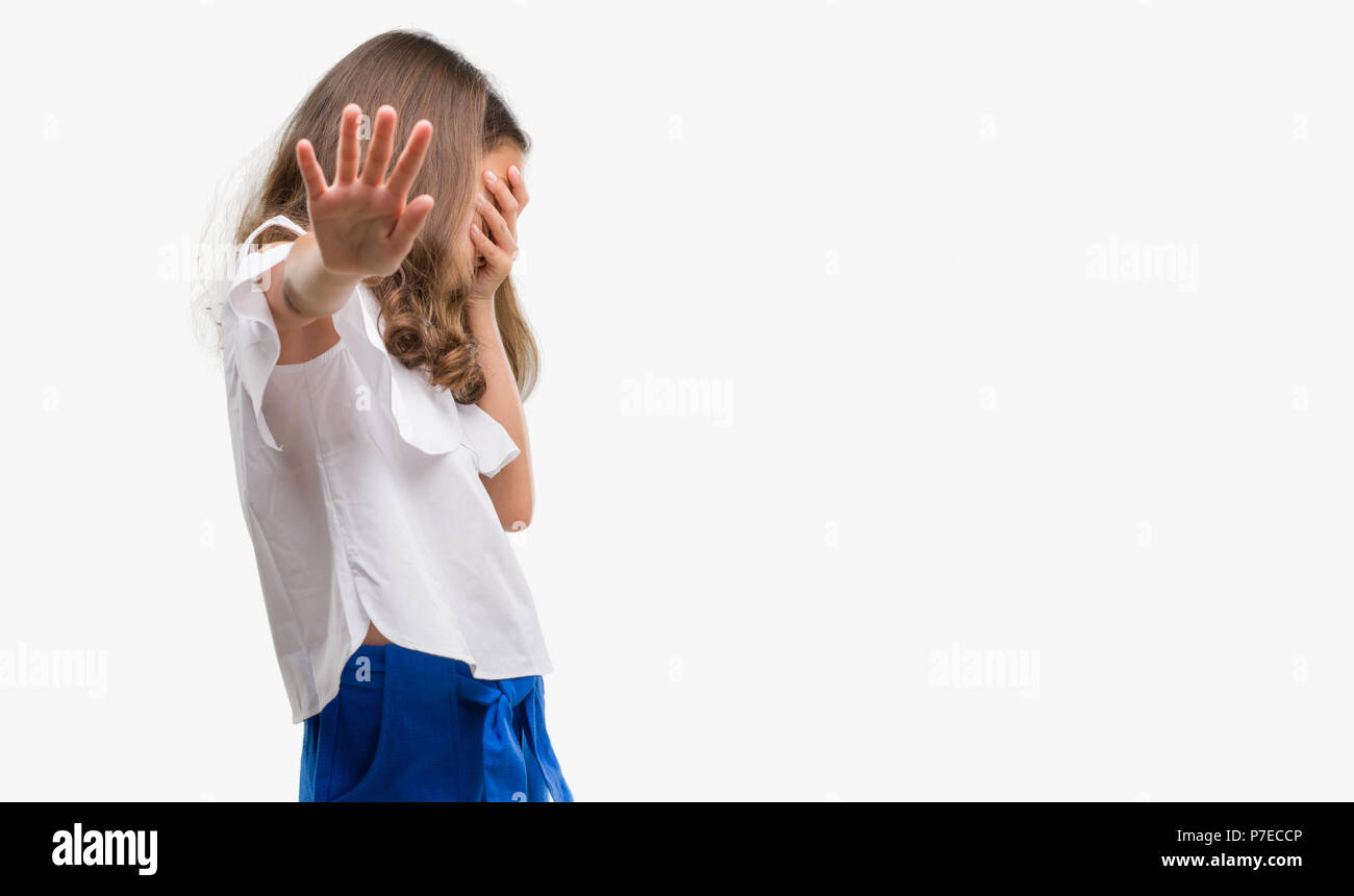 Brunette hispanic girl covering eyes with hands and doing stop gesture with sad and fear expression. Embarrassed and negative concept. Stock Photo