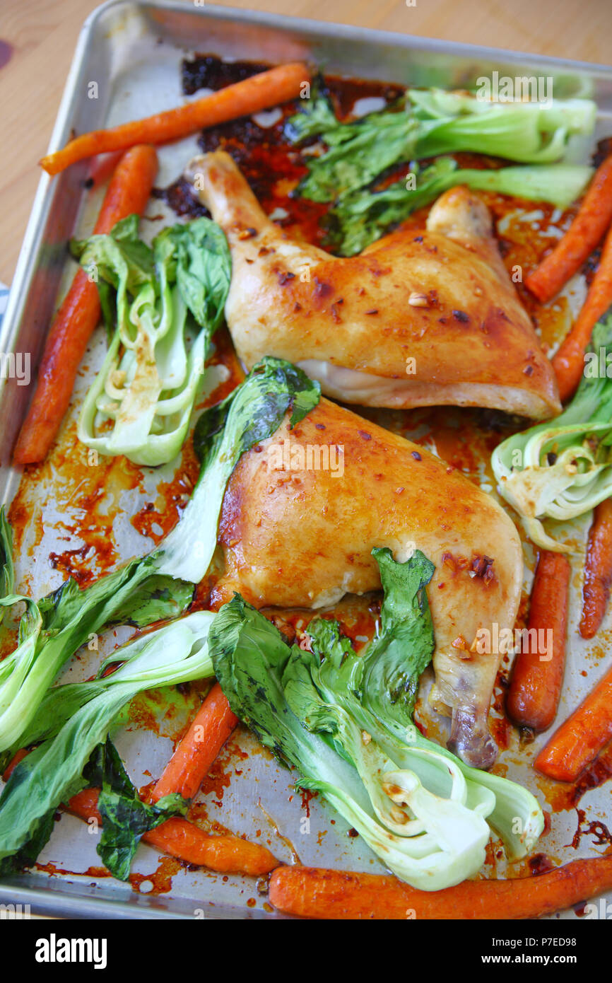 Roast chicken quarters with baby bok choy and carrots in a sheet pan