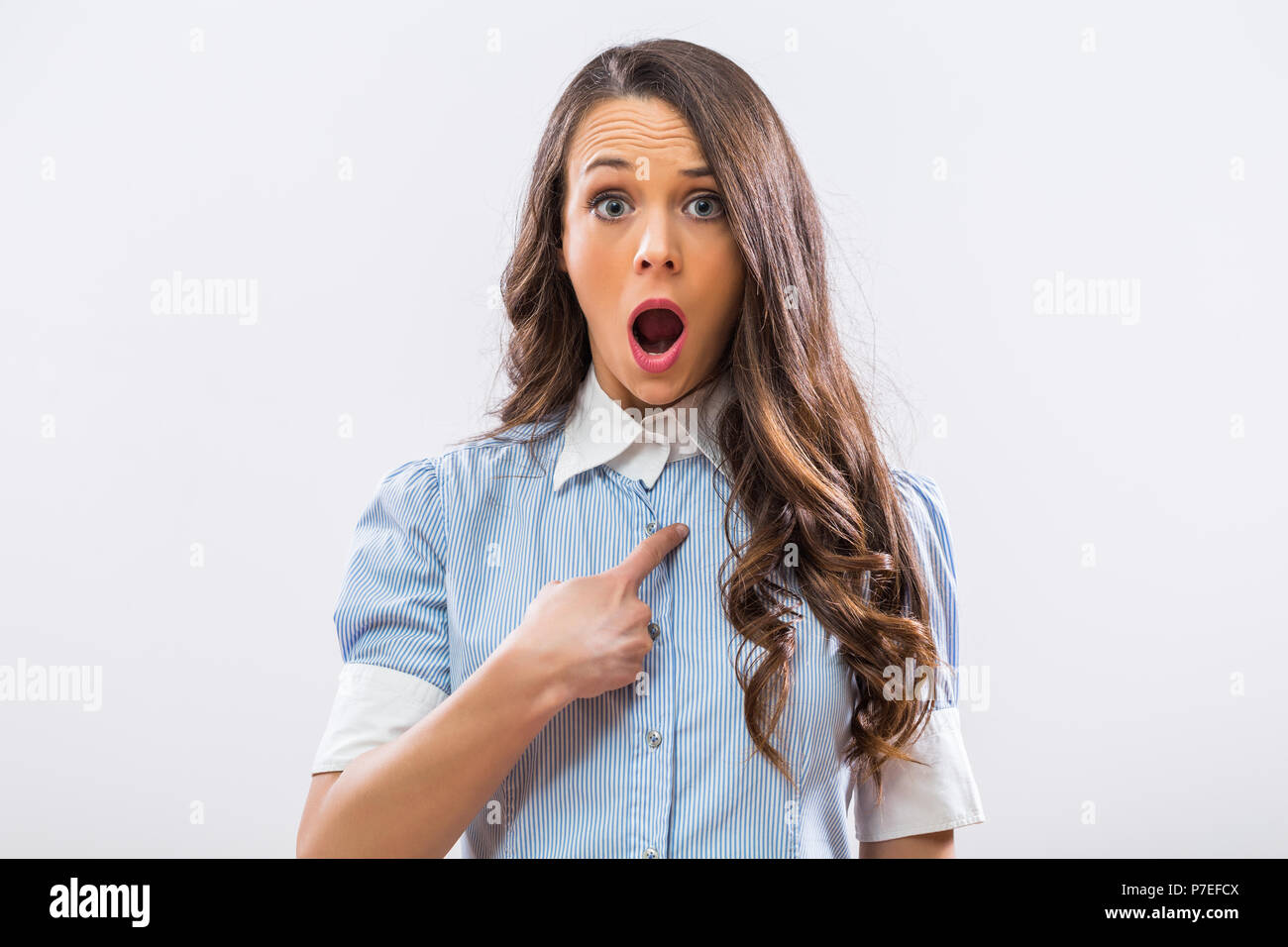 Image of shocked businesswoman pointing at herself on gray background. Stock Photo