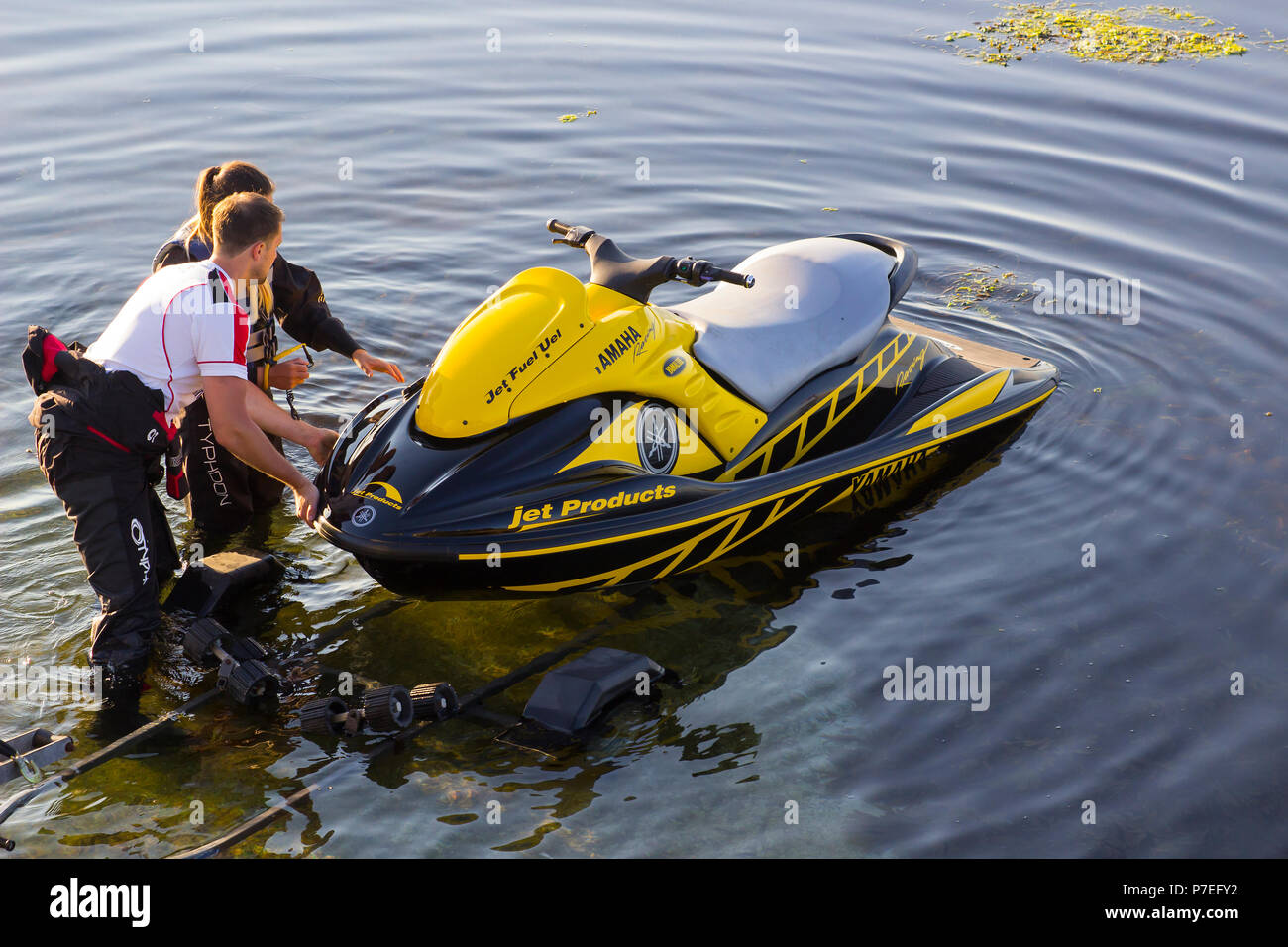 29 June 2018 a young couple in wet gear pushing a powerful Yamaha Jet-Ski off its trailer into the sea at Groomsport Harbour Northern Ireland Stock Photo