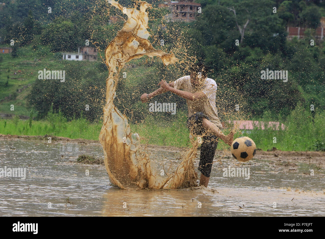 A man playing a football in a muddy field during the National Paddy Day outskirt of Kathmandu, Nepal. Sarita Khadka/Alamy Live News Stock Photo
