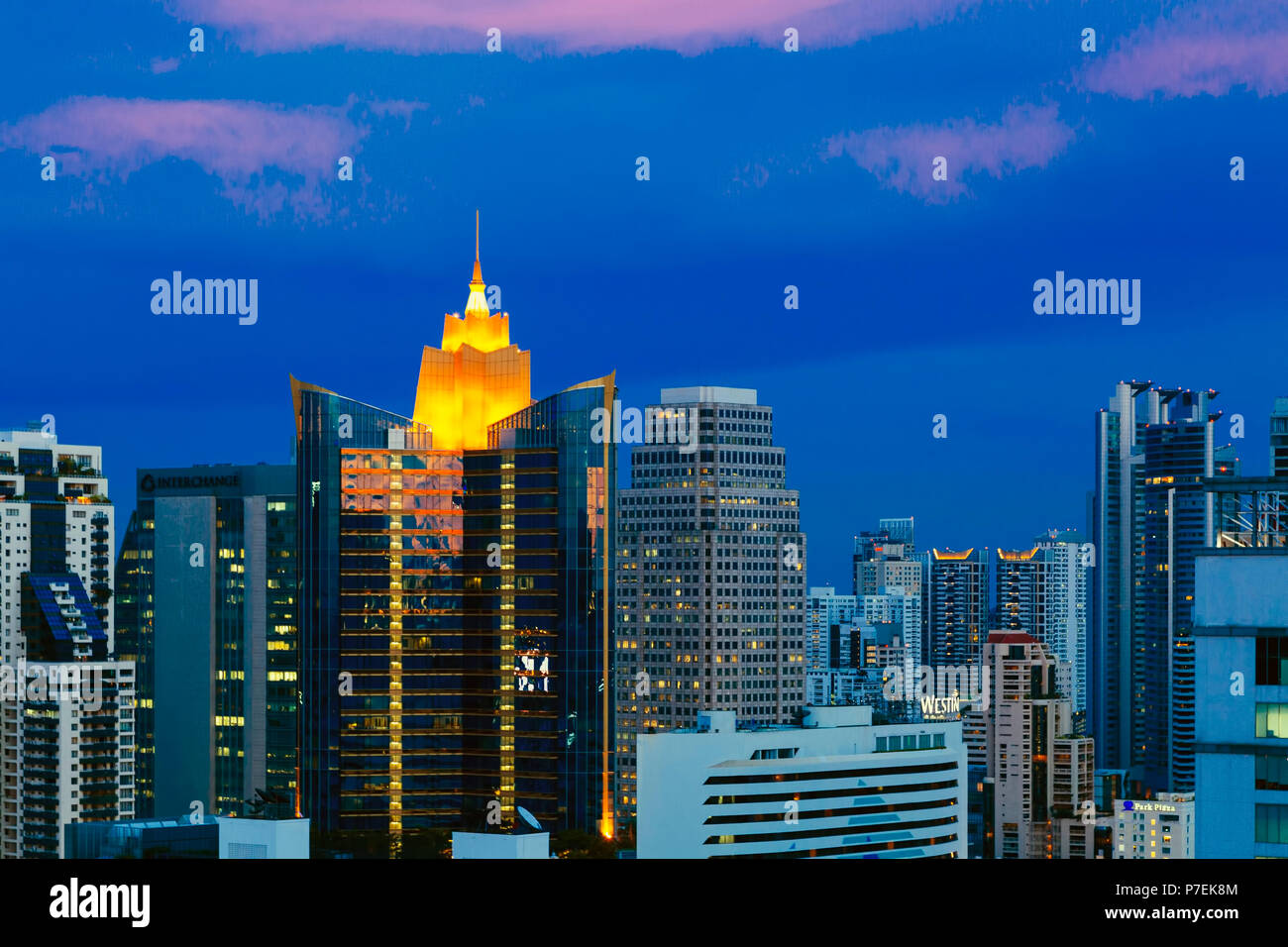 Lights coming on at sunset on skyline of high rise buildings in Bangkok ...