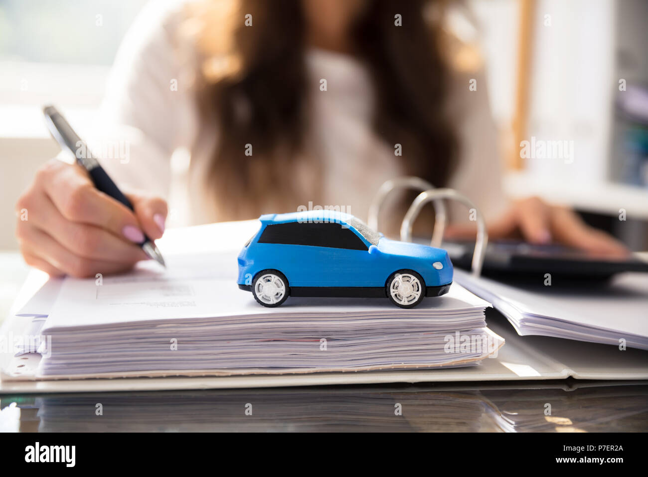 Businesswoman Working On Documents With Small Blue Car Stock Photo