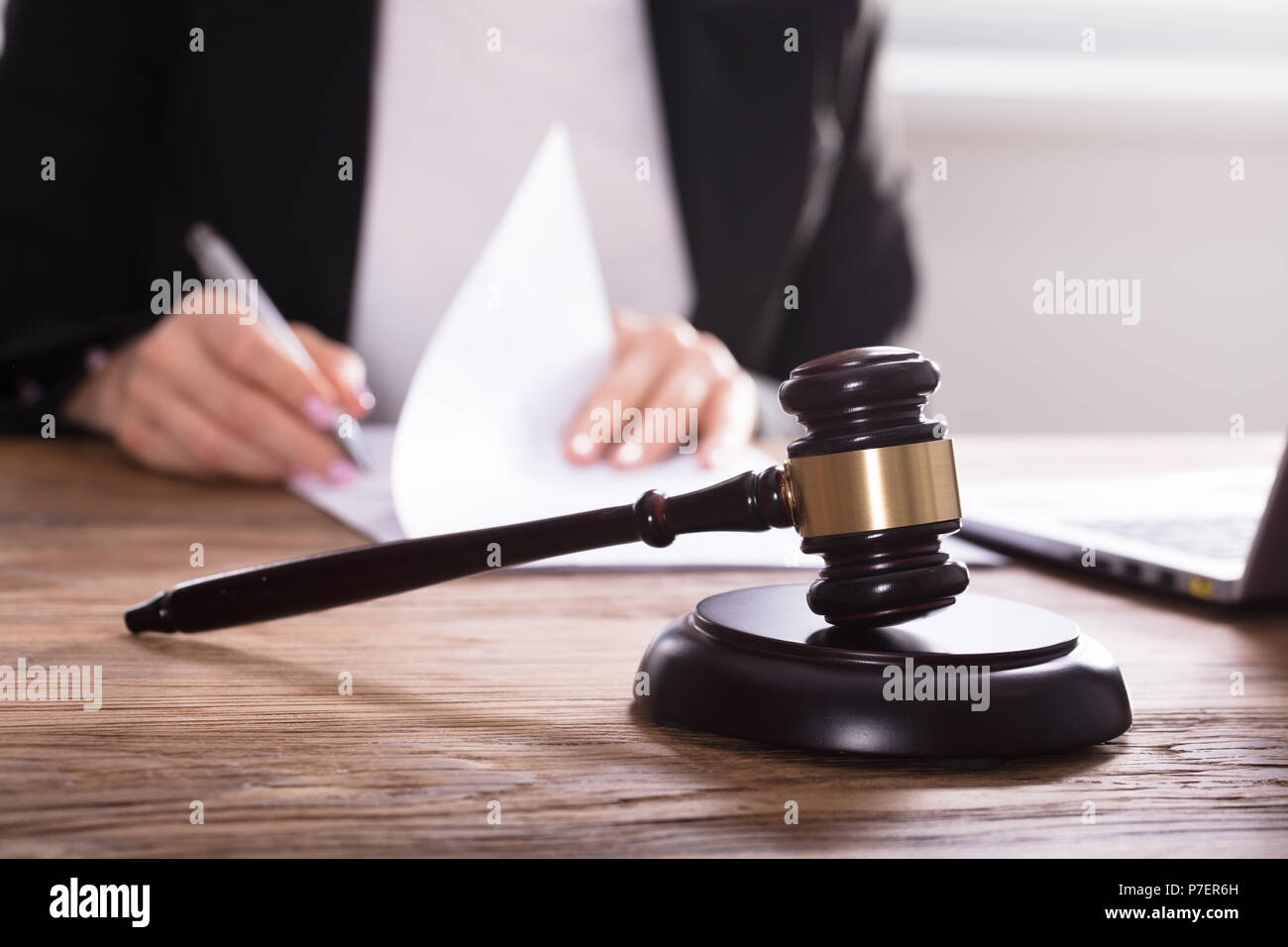 Close-up Of Gavel In Front Of Judge Working On Document Stock Photo