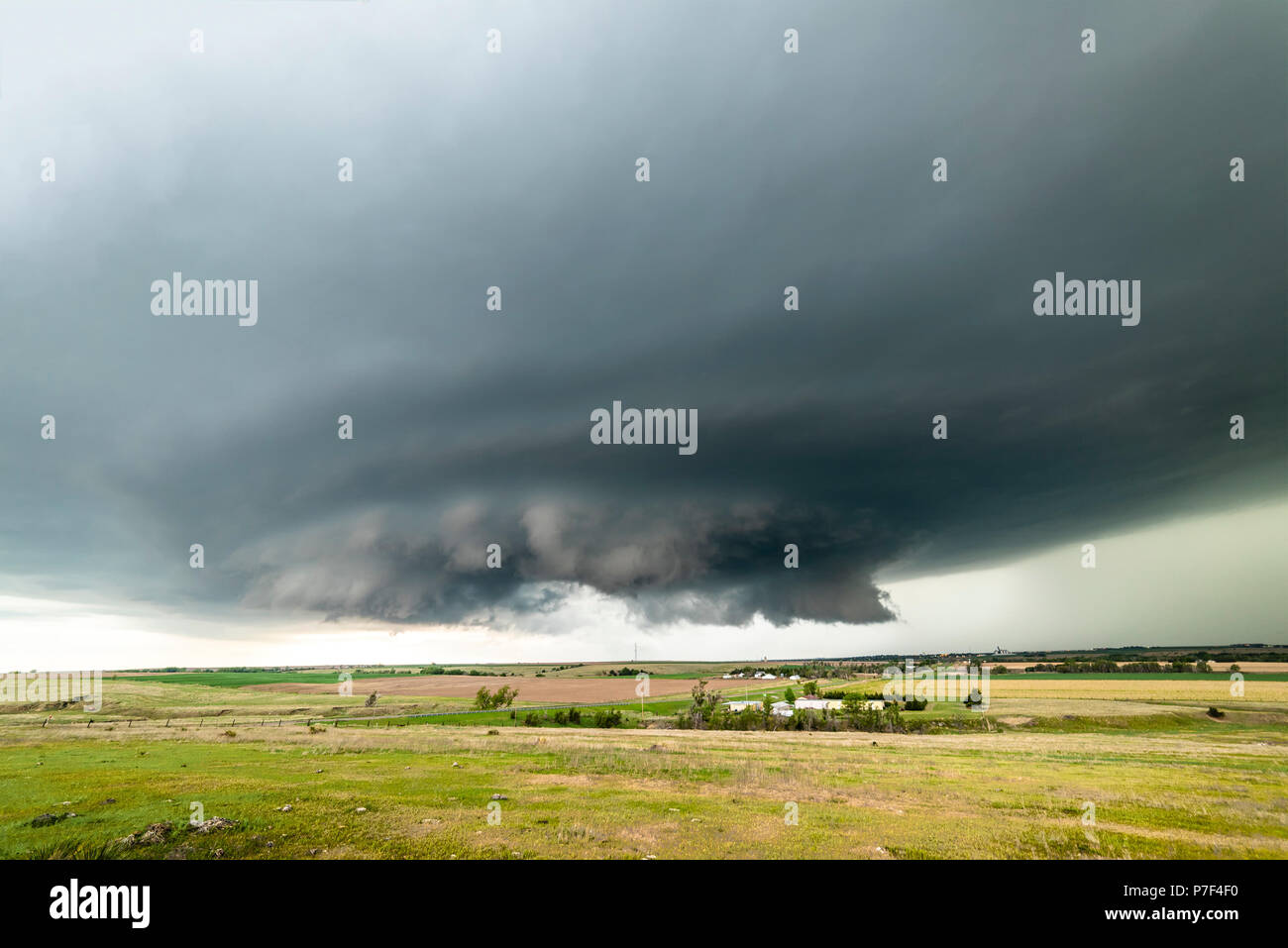 Large, powerful tornadic supercell storm moving over a small town in 