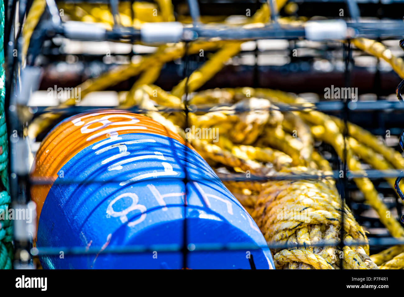 Crab pot fishing gear with yellow coiled polypropylene rope and buoys waiting to be launched into the ocean to catch seafood. Stock Photo