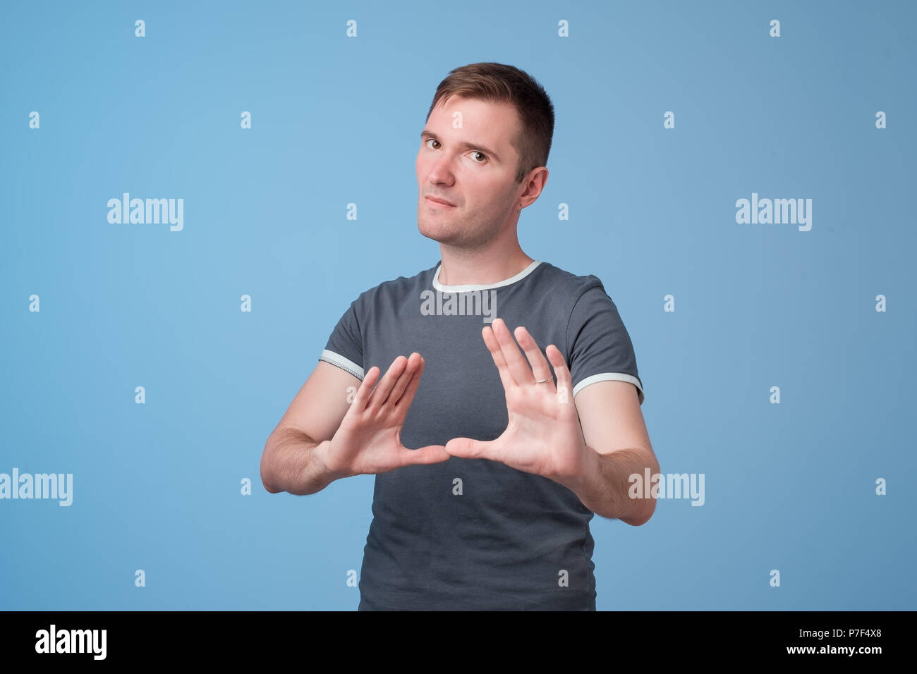Portrait of european serious young man stretching hand towards camera with stop or hold gesture Stock Photo