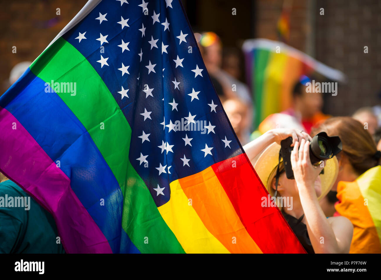 American flag with stars and gay pride rainbow stripes being waved at the annual Gay Pride Parade in Greenwich Village, NYC Stock Photo