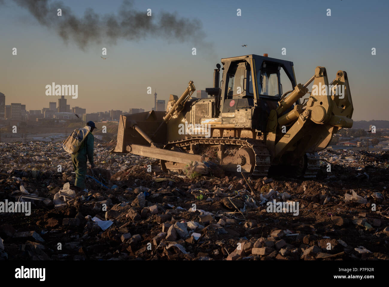 A picker following a front loader collecting recyclable refuse at the Robinson Deep landfill in South Africa's commercial capital of Johannesburg Stock Photo