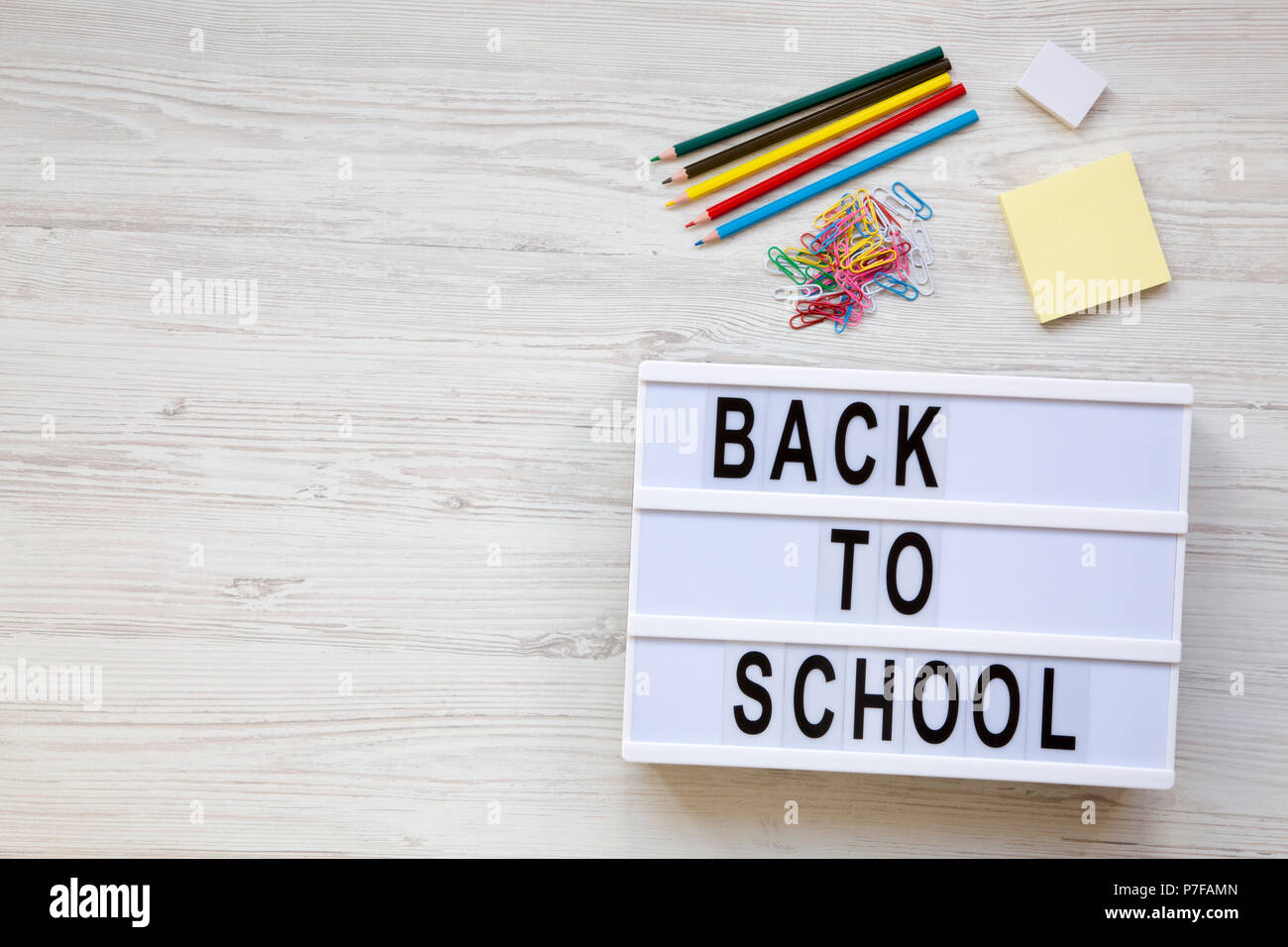 Education concept. Eraser, pencils, stickers, paper clips and 'Back to school' word on a modern board over a white wooden surface. From above, overhea Stock Photo