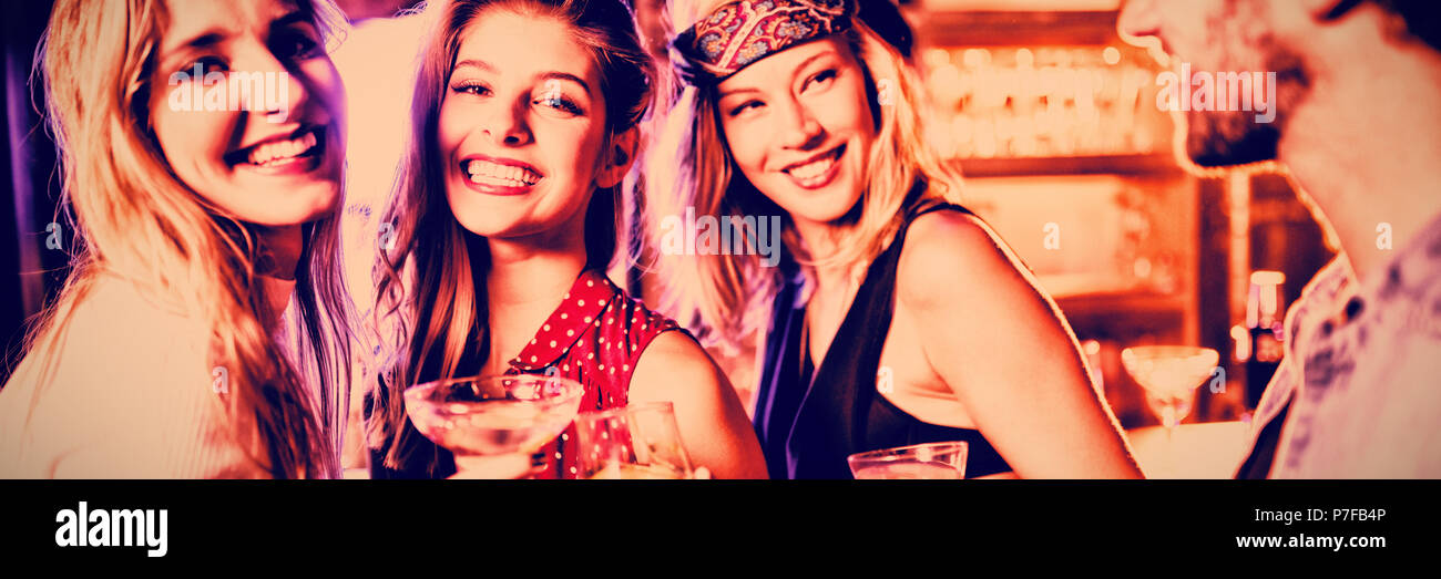 Women with male friend at counter in nightclub Stock Photo