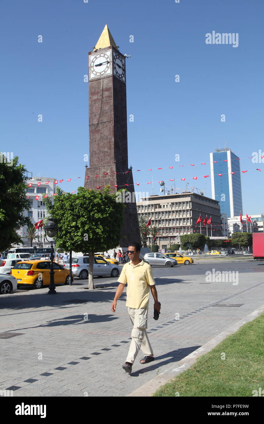 Man walking by clock tower and park at Habib Bourguibe avenue in Tunis, the capital of Tunisia on a sunny summer day Stock Photo