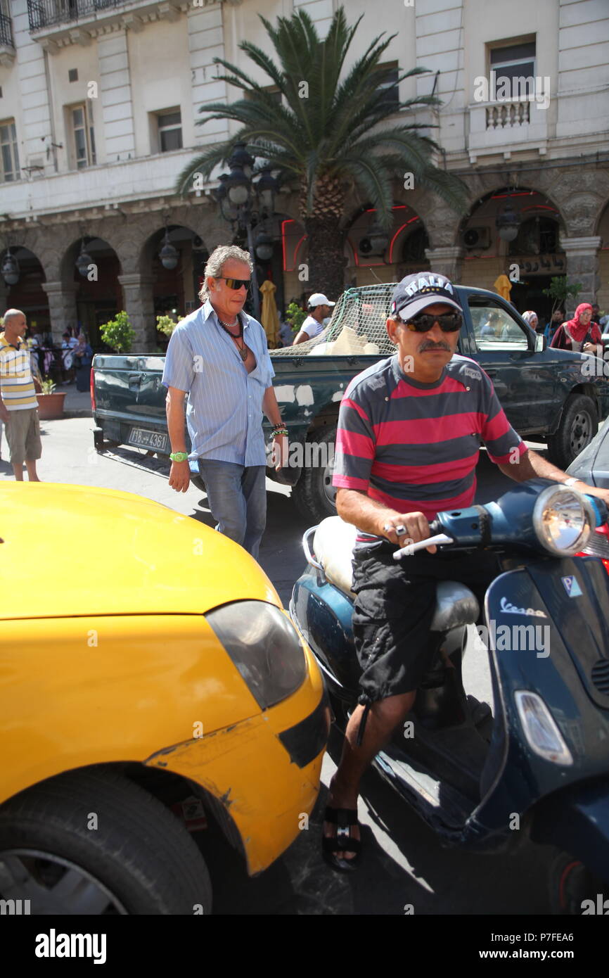 Tight traffic on the street of Tunis, the capital of Tunisia, with local resident is paving his way on scooter Stock Photo
