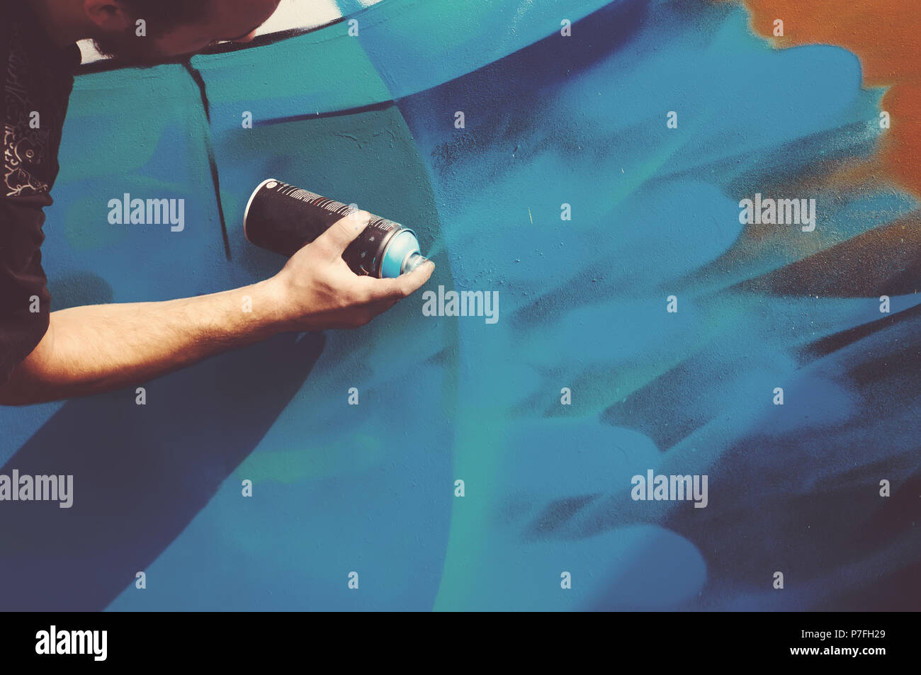 Close up with young boy doing graffiti, holding spray can with hand