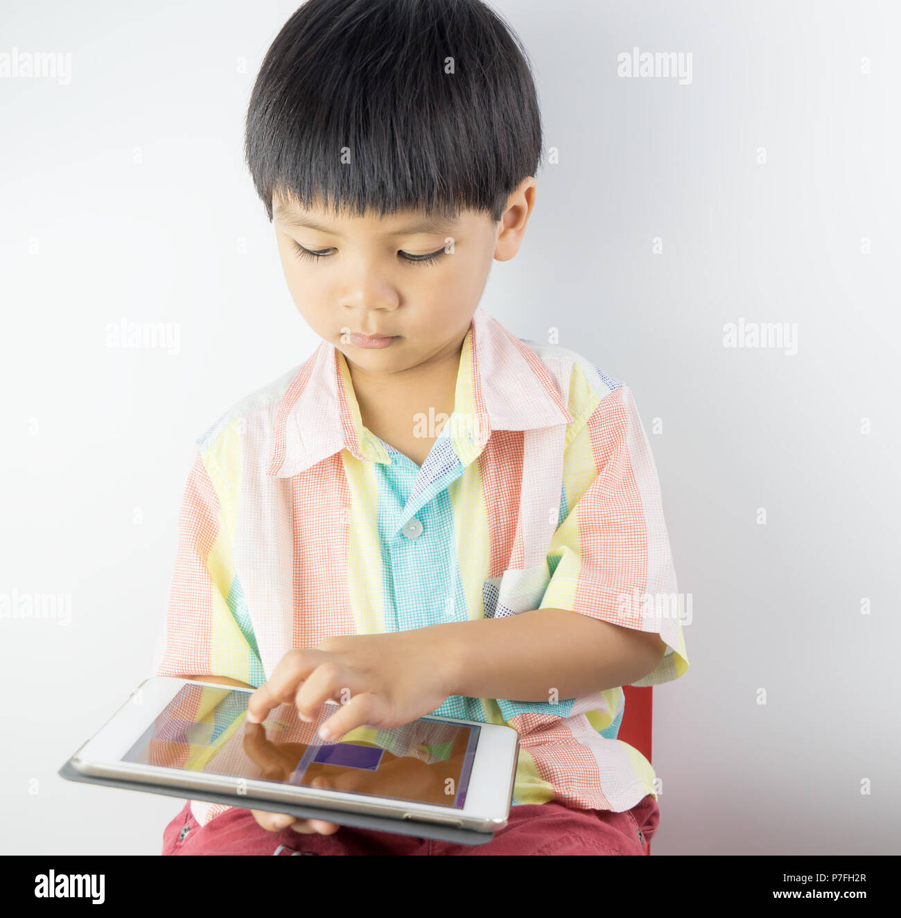 Asian boy is using finger to touch Tablet screen. Stock Photo