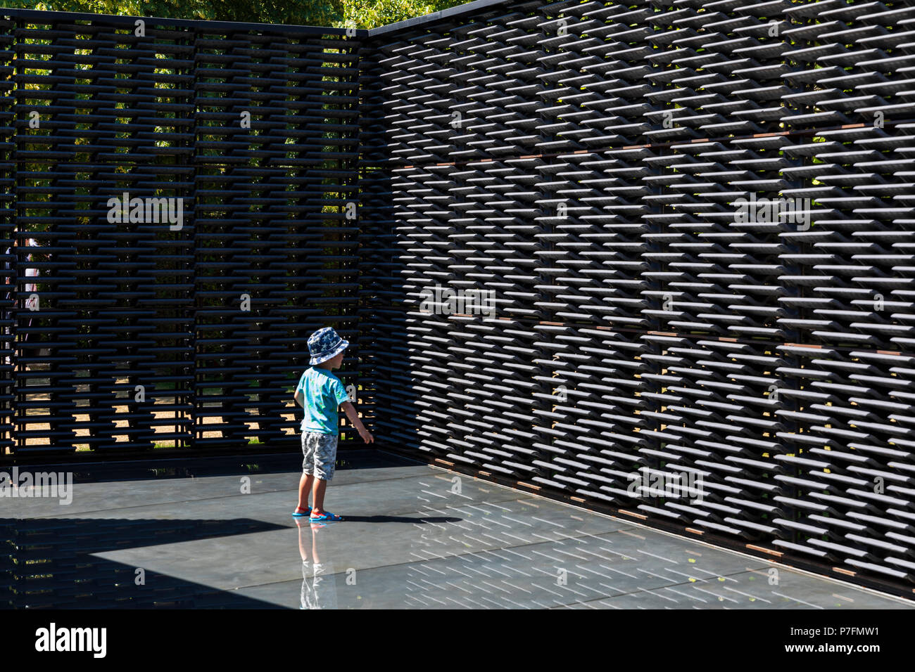 A young boy stands in the interior pool of the Serpentine Pavilion 2018 designed by the architect Frida Escobedo. Stock Photo