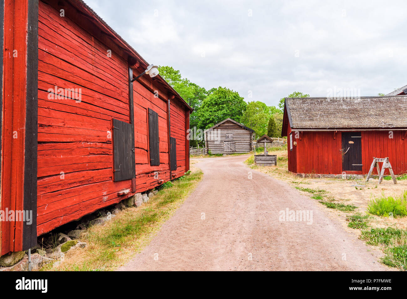 Vintage Village Well Beside A Gravel Road And Some Barns Homes In