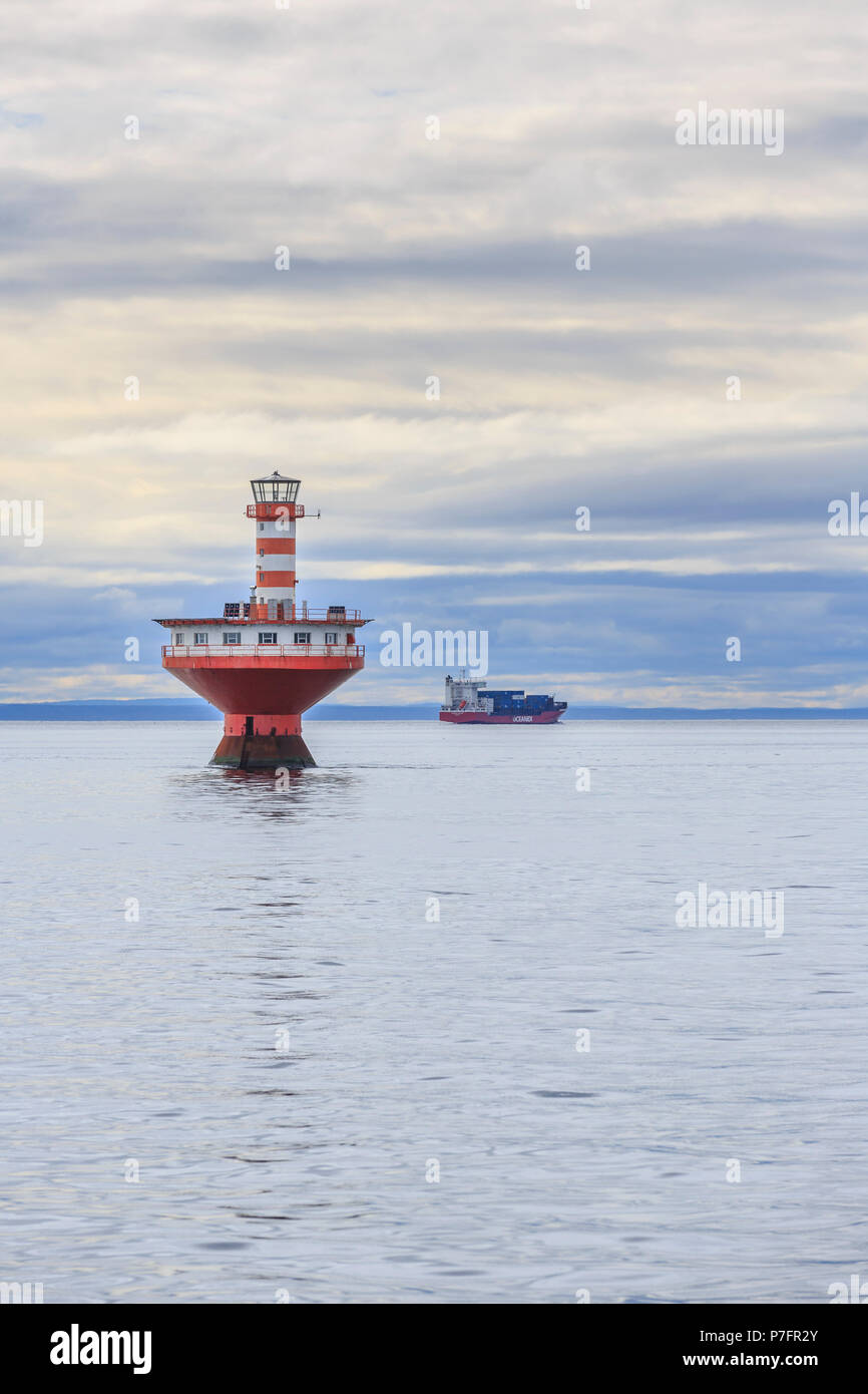 Lighthouse Phare du Haut-Fond Prince in Saint Lawrence River with freighter in the back, Tadoussac, Québec Province, Canada Stock Photo