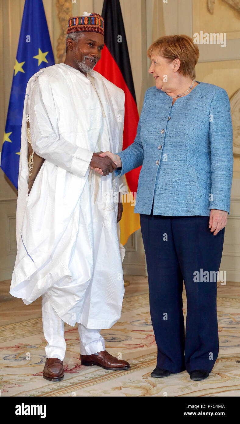 Germany, Meseberg. 6th July, 2018. German chancellor Angela Merkel (CDU) shakes hands with Yusuf Maitama Tuggar (L), embassador of Nigeria during the reception for the Diplomatic corps, an annual traditional event held at the baroque palace Meseberg. Credit: Wolfgang Kumm/dpa/Alamy Live News Stock Photo