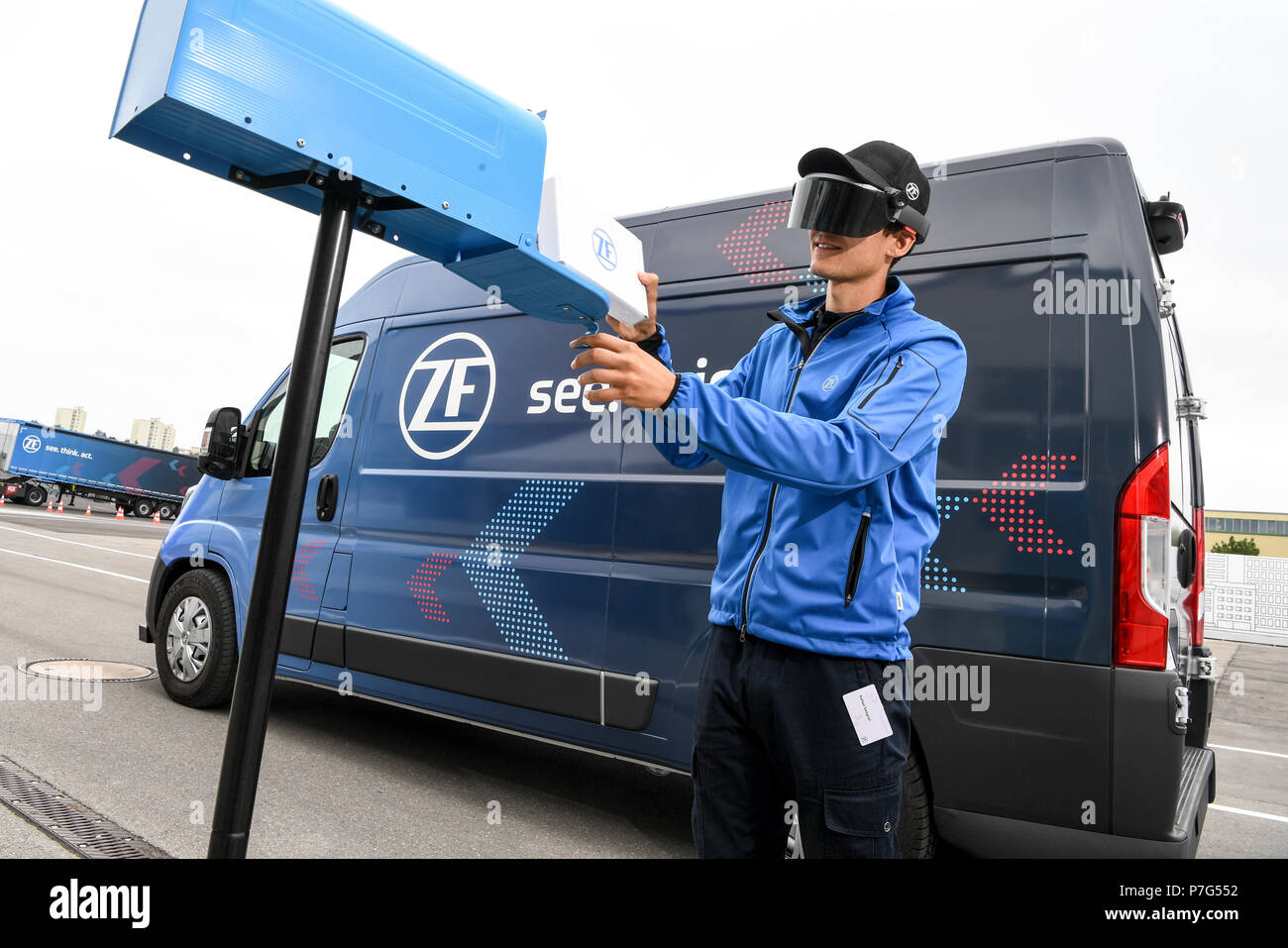 27 June 2018, Friedrichshafen, Germany: A ZF employee carries a package while the ZF Innovation Van drives on by itself, for example to move out of a no-parking zone. A pair of data glasses provides delivery personnel with information on the next stop. Photo: Felix Kästle/dpa Stock Photo