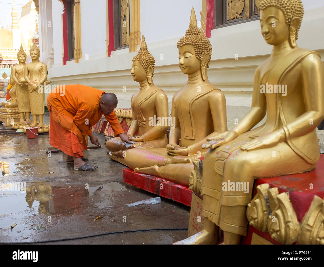 Buddhist monk cleaning Buddha statues at Wat Pha That Luang temple