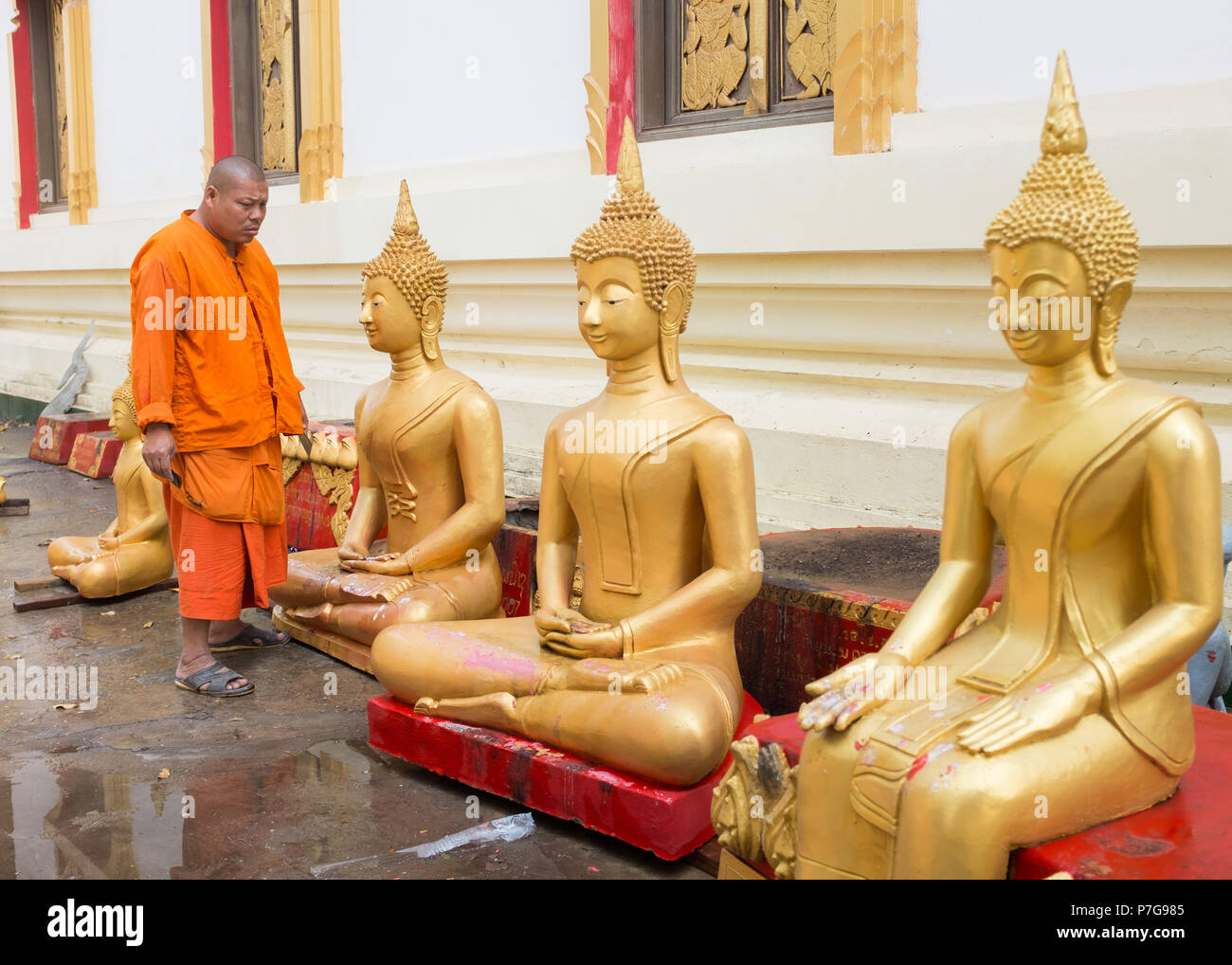 Buddhist monk cleaning Buddha statues at Wat Pha That Luang temple